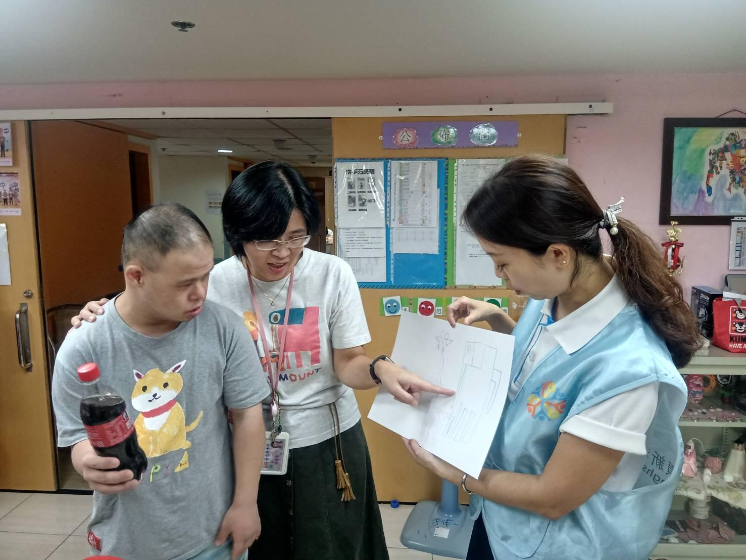 樂山教養院院生「畢卡平」(左)送他的畫給頂新和德文教基金會副執行長蕭巧怡(右),基金會回贈他愛喝的可樂。(頂新和德文教基金會提供)