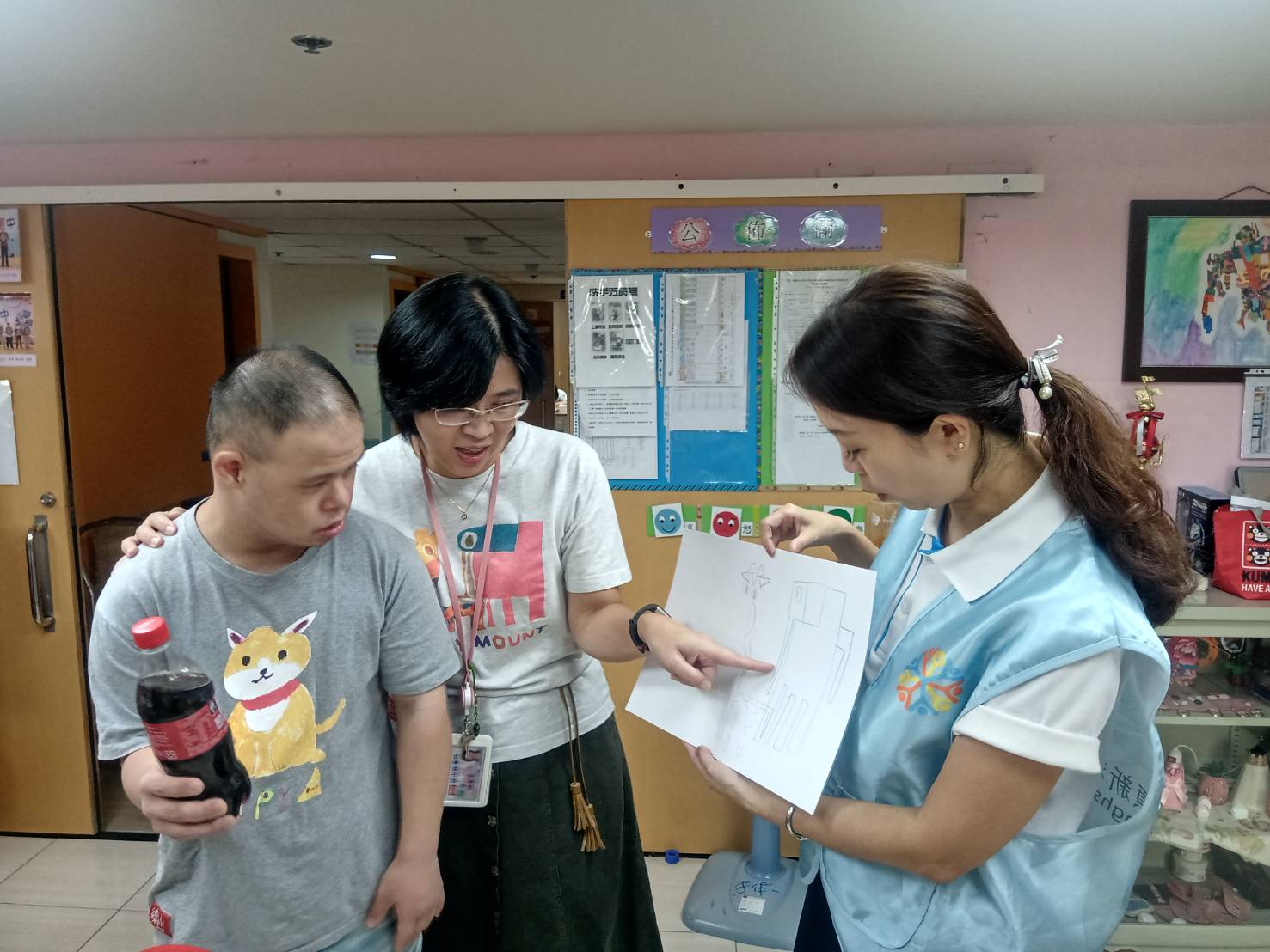 樂山教養院院生「畢卡平」（左）送他的畫給頂新和德文教基金會副執行長蕭巧怡（右），基金會回贈他愛喝的可樂。（頂新和德文教基金會提供）