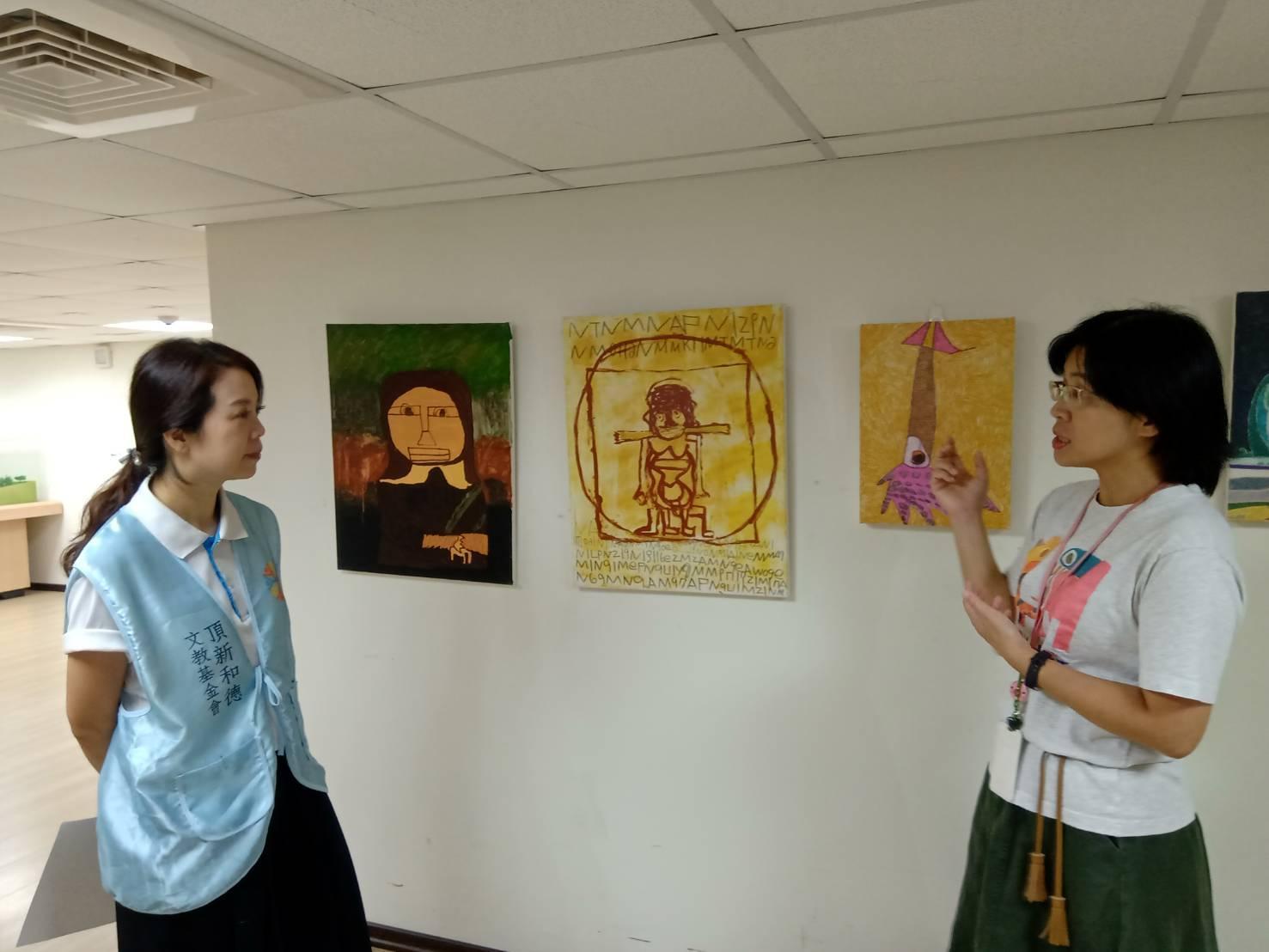 樂山教養院院長張嘉芳(右)向頂新和德文教基金會副執行長蕭巧怡介紹院生創作的畫廊。(頂新和德文教基金會提供)