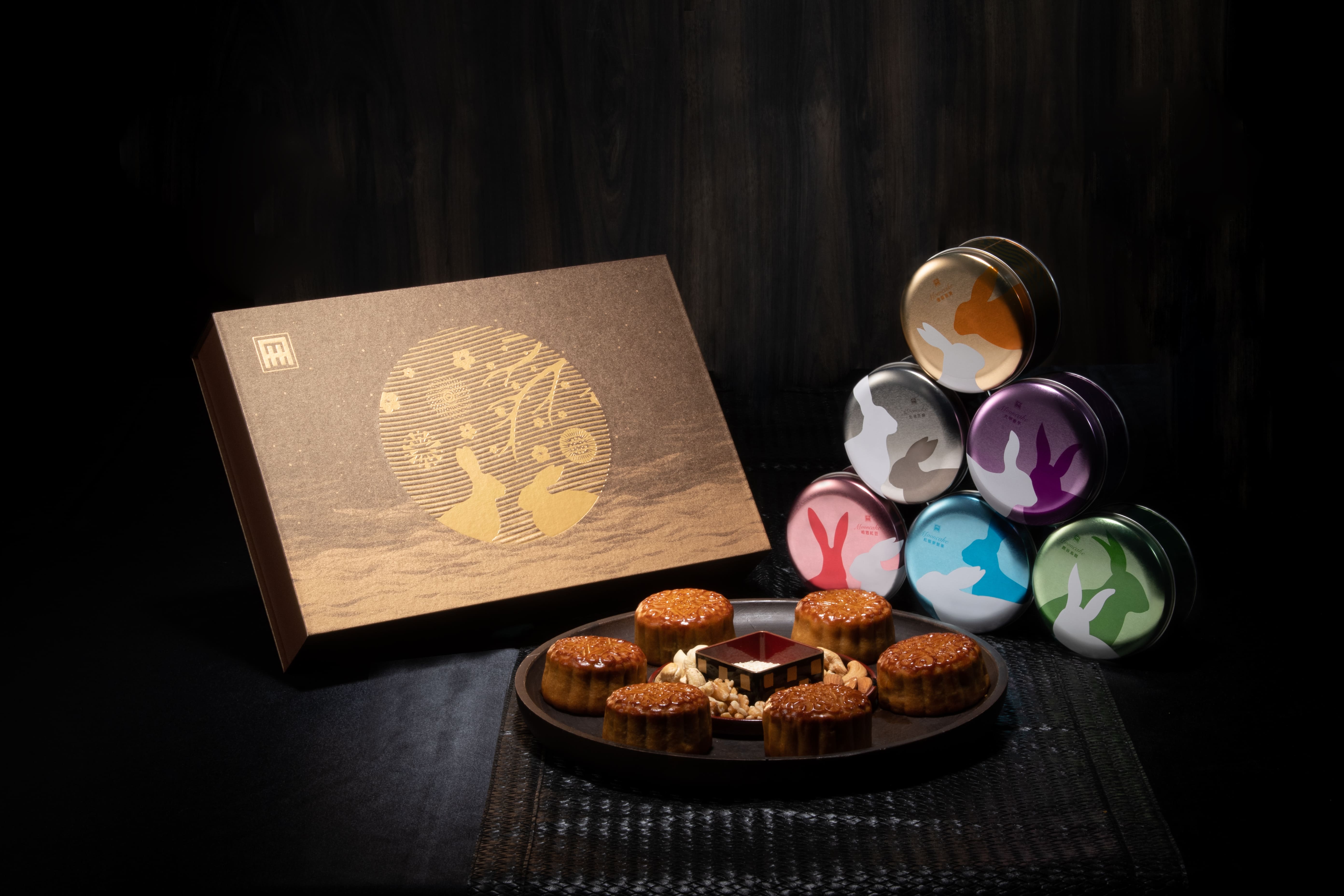 國賓【月映金秋】六入月餅禮盒／定價NT$1,380 (蓮蓉蛋黃、相思紅豆、鹿谷烏龍、北港芝麻、大甲香芋、紅藜麥堅果) 透過下方金沙的流動，以及中心的明月剪影與其中元素，呈現「流金歲月，風華無限」的寓意，整體設計典雅奢華。內盒設計選用經典圓形馬口鐵盒，兼具收納功能，上方繽紛的玉兔剪影，象徵中秋豐富多采、玉兔呈祥。