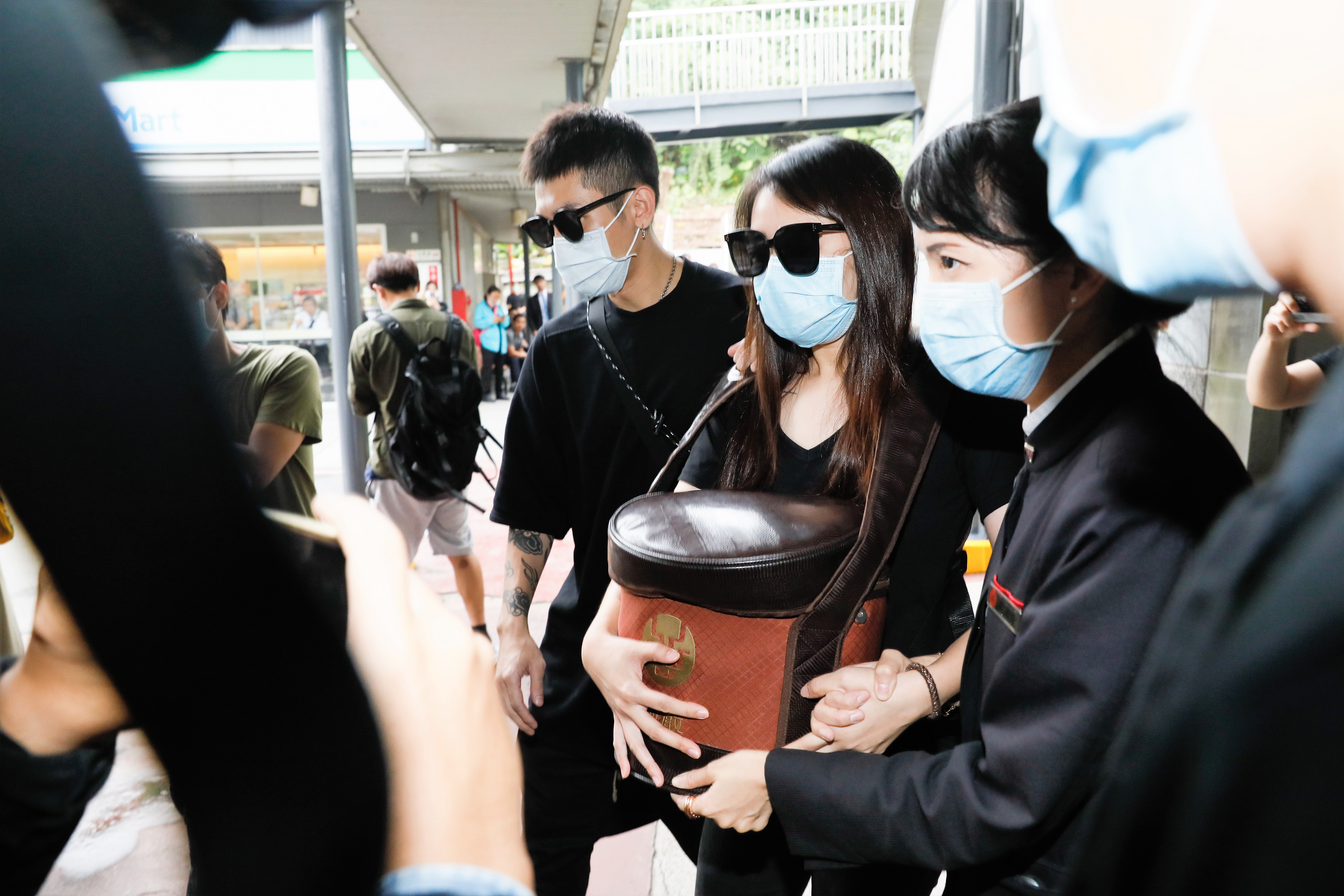 小鬼黃鴻升火化完成後，由妹妹親捧哥哥骨灰離開。