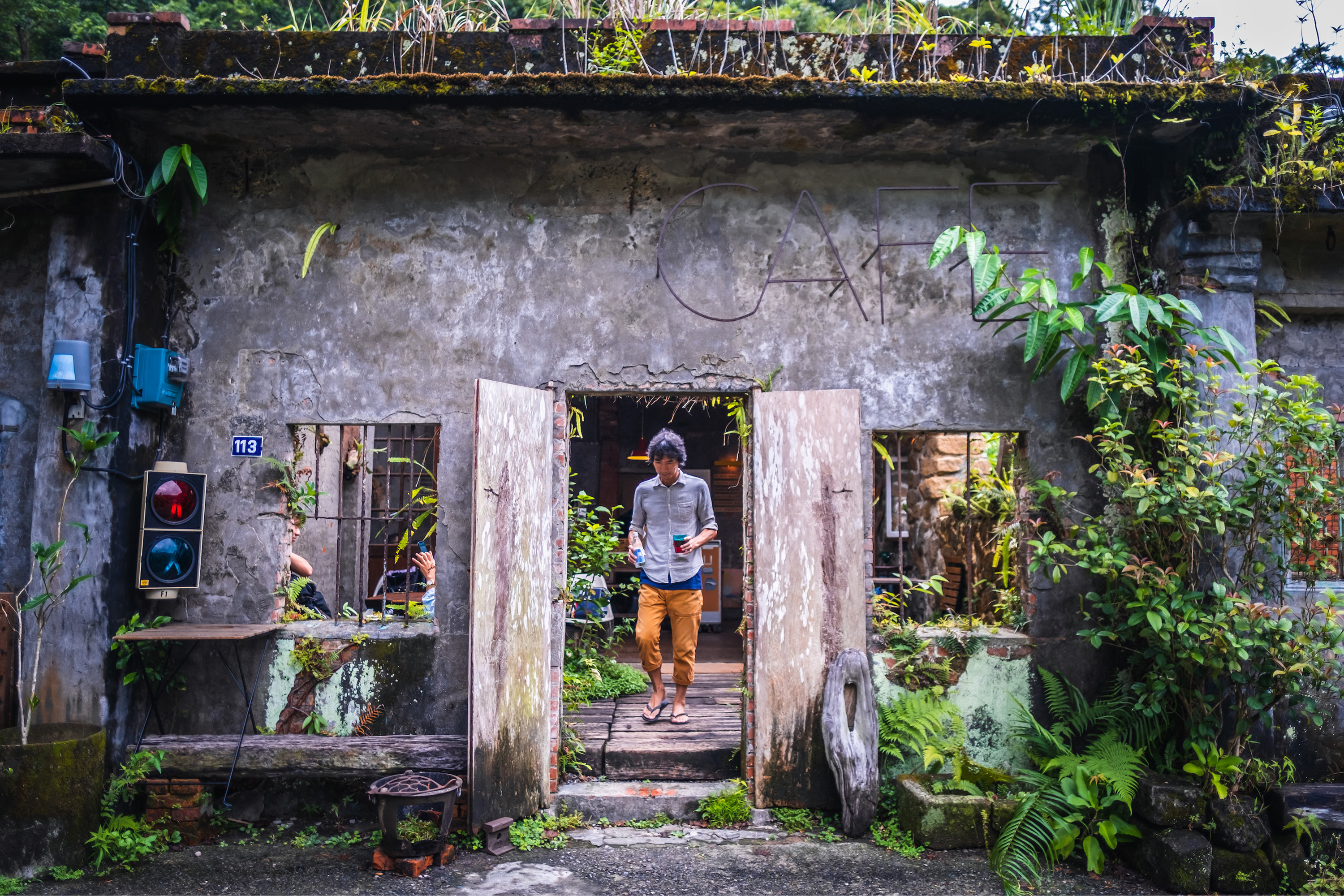 咖啡館的正面記錄了歲月流逝的痕跡，草叢蕨類自然生長伴隨民宅聚落。
