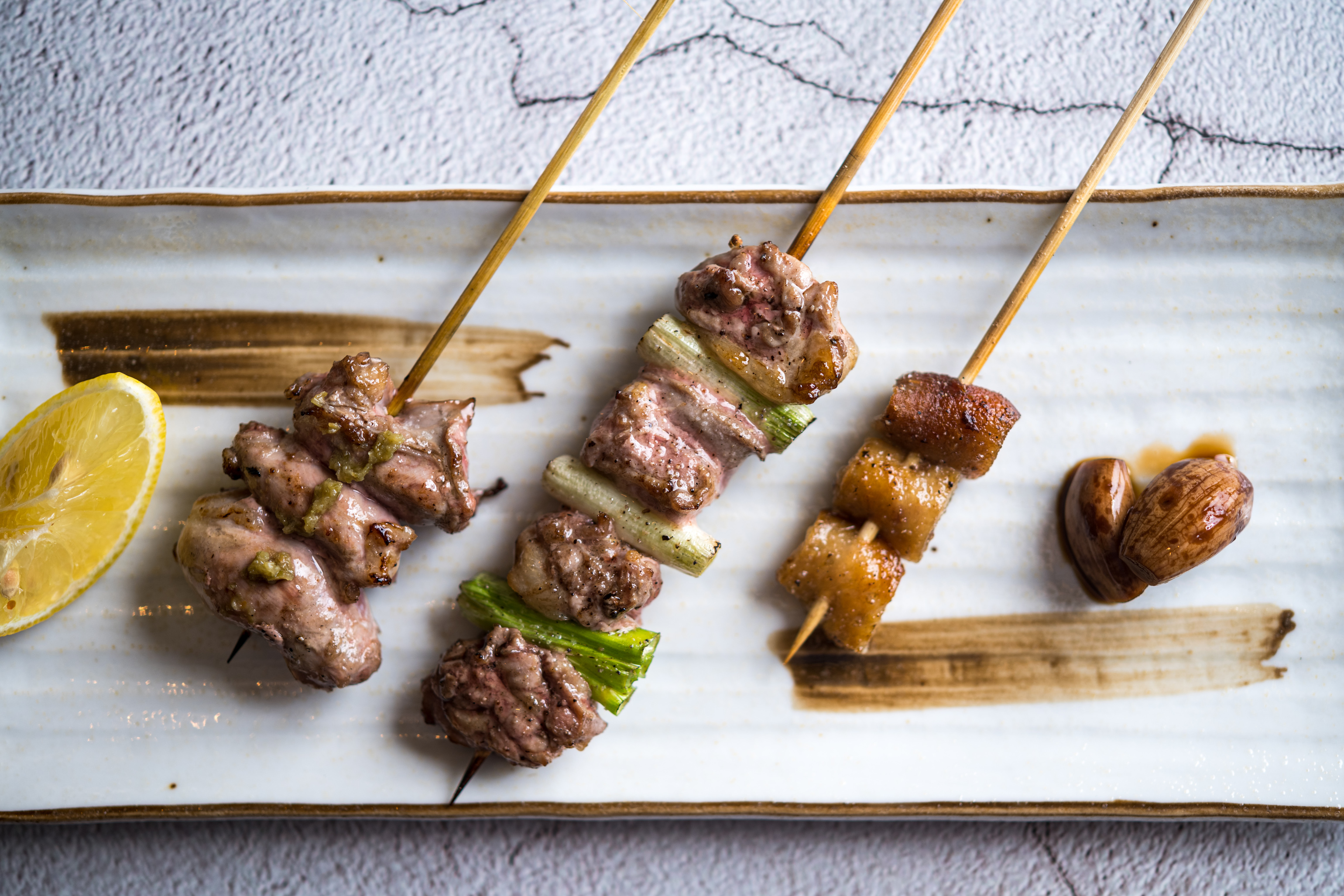 John用鴨皮、腿肉佐蔥、阿基里斯腱佐柚子胡椒的「三種鴨腿串燒」呼應混釀芋燒酎的三種面貌。（300元／份）