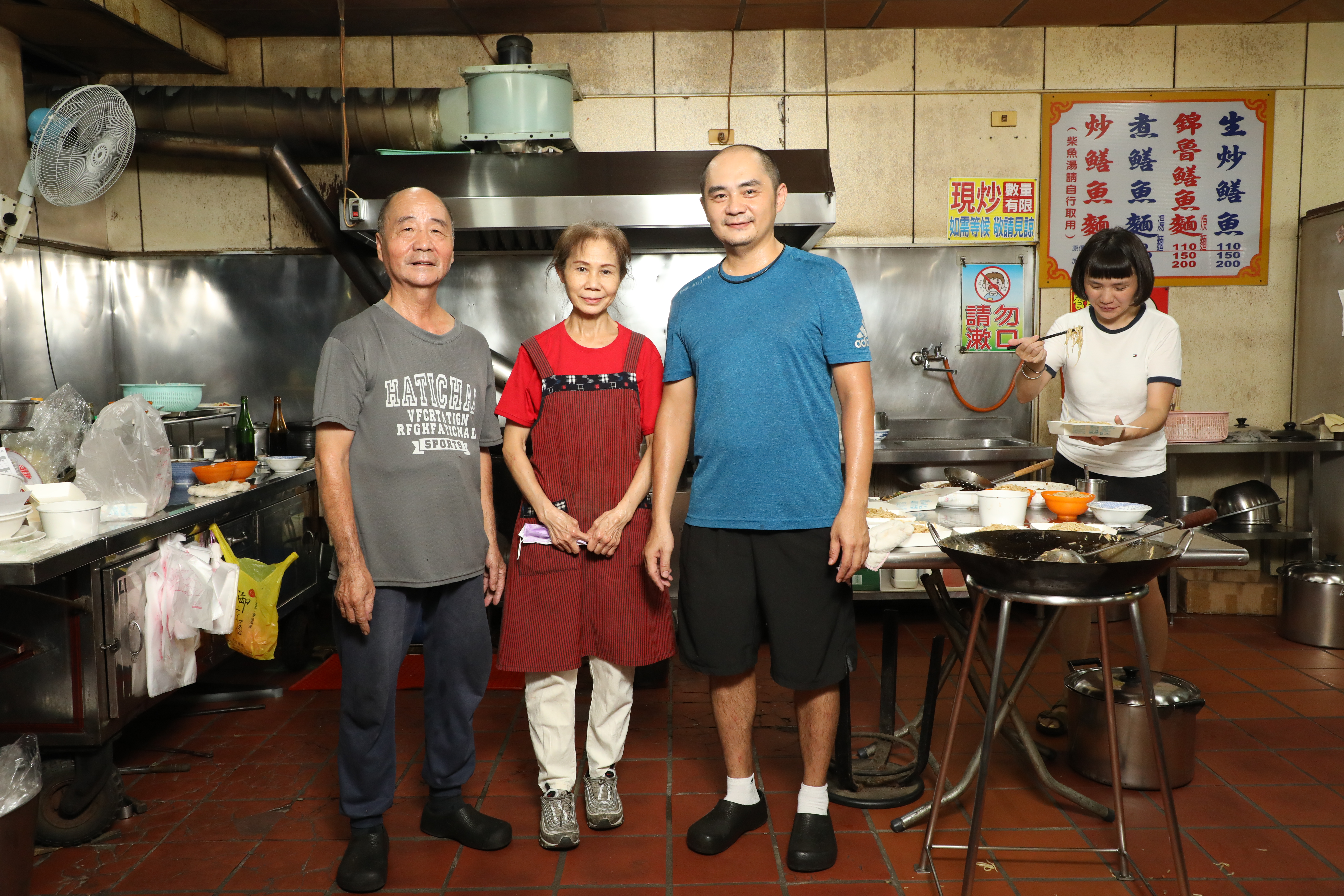 第一代老闆娘曾宏月（中）負責切鱔魚肉，老闆鍾焜吉（左）和兒子鍾承邵（右）負責炒麵。