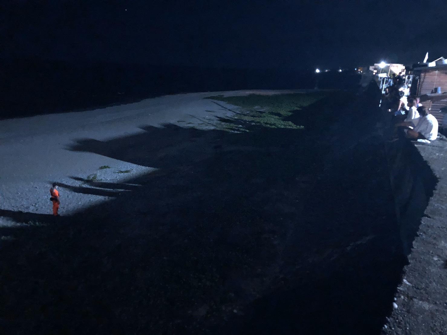海巡人員在距離綠蠵龜約10公尺處進行戒護，並向周遭遊客柔性勸導切勿大聲喧嘩及開啟任何燈源等事項，以維持現場環境使綠蠵龜能順利產卵。（海巡署提供）