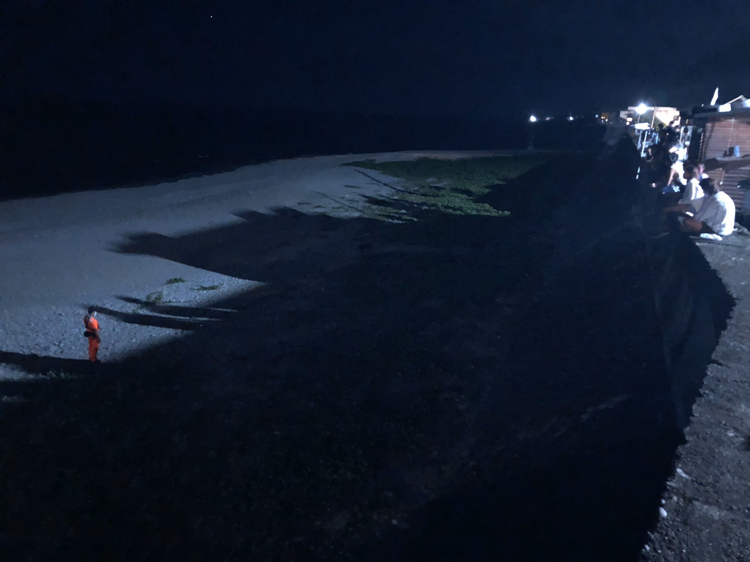 海巡人員在距離綠蠵龜約10公尺處進行戒護,並向周遭遊客柔性勸導切勿大聲喧嘩及開啟任何燈源等事項,以維持現場環境使綠蠵龜能順利產卵。(海巡署提供)