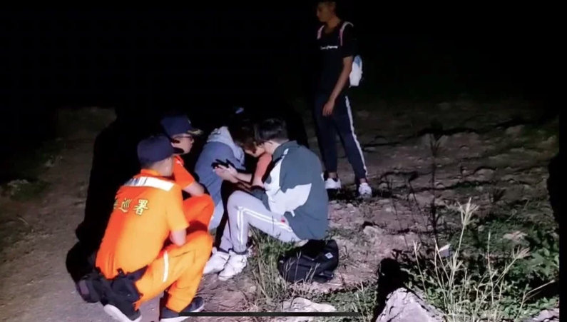 1名年約50歲的紅衣女子坐在礁岩上哭泣，4名中山大學學生勇敢上前並且報案求助。（翻攝畫面）
