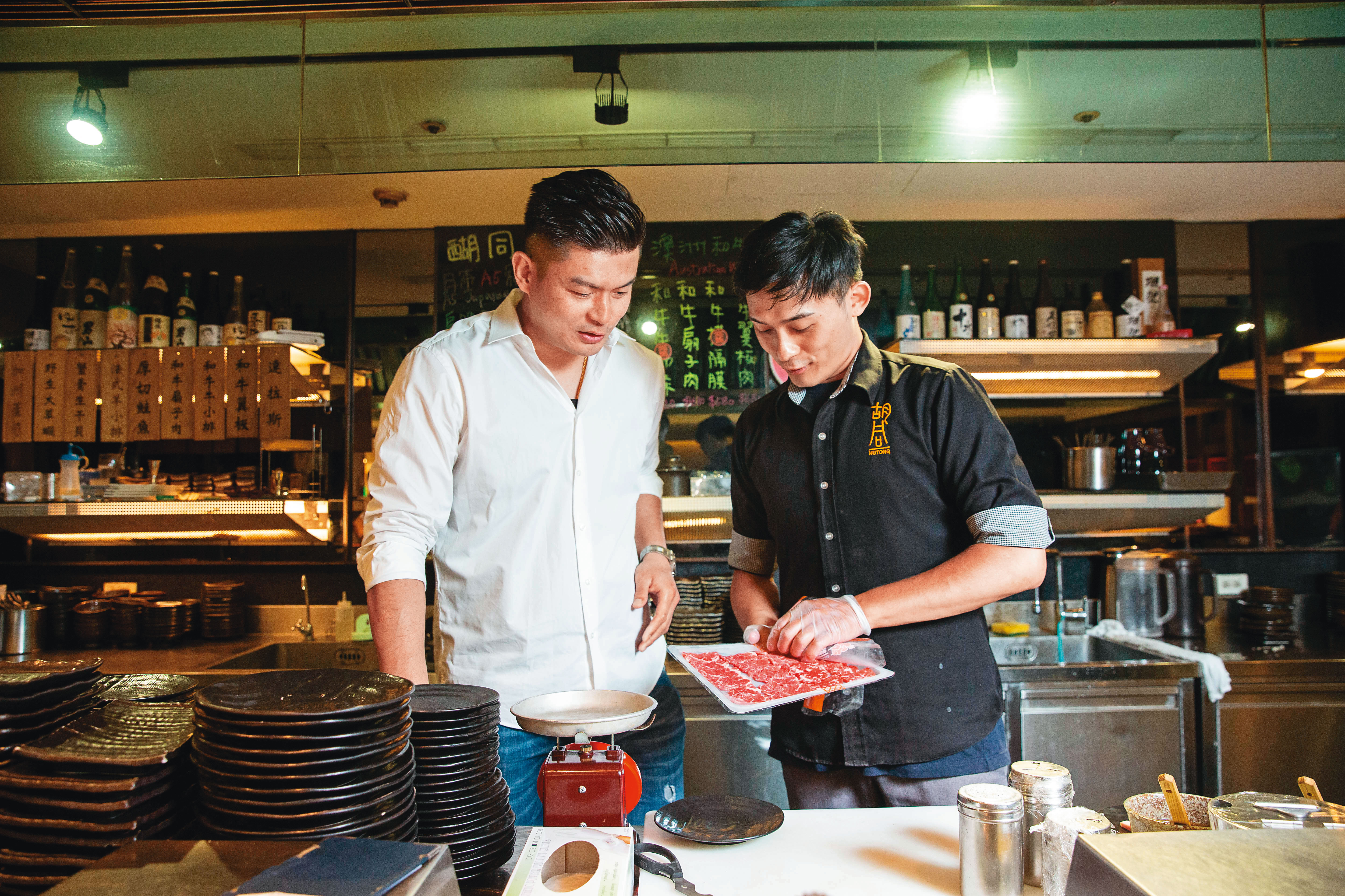 吳念忠（左）巡視店面時，再次檢視肉品品質是否合格。