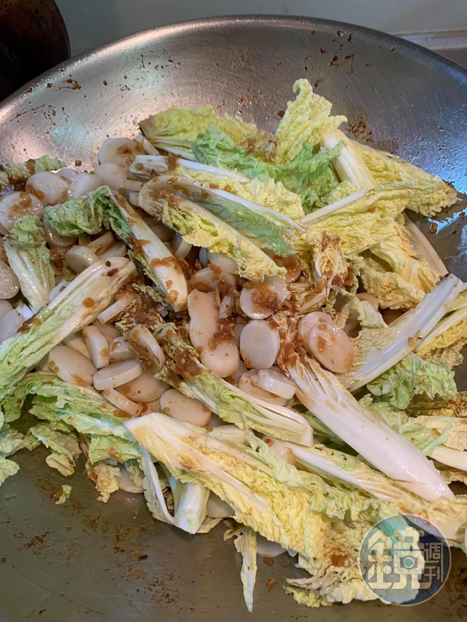 將蟹塊撈出，留下的醬汁炒年糕與蔬菜。