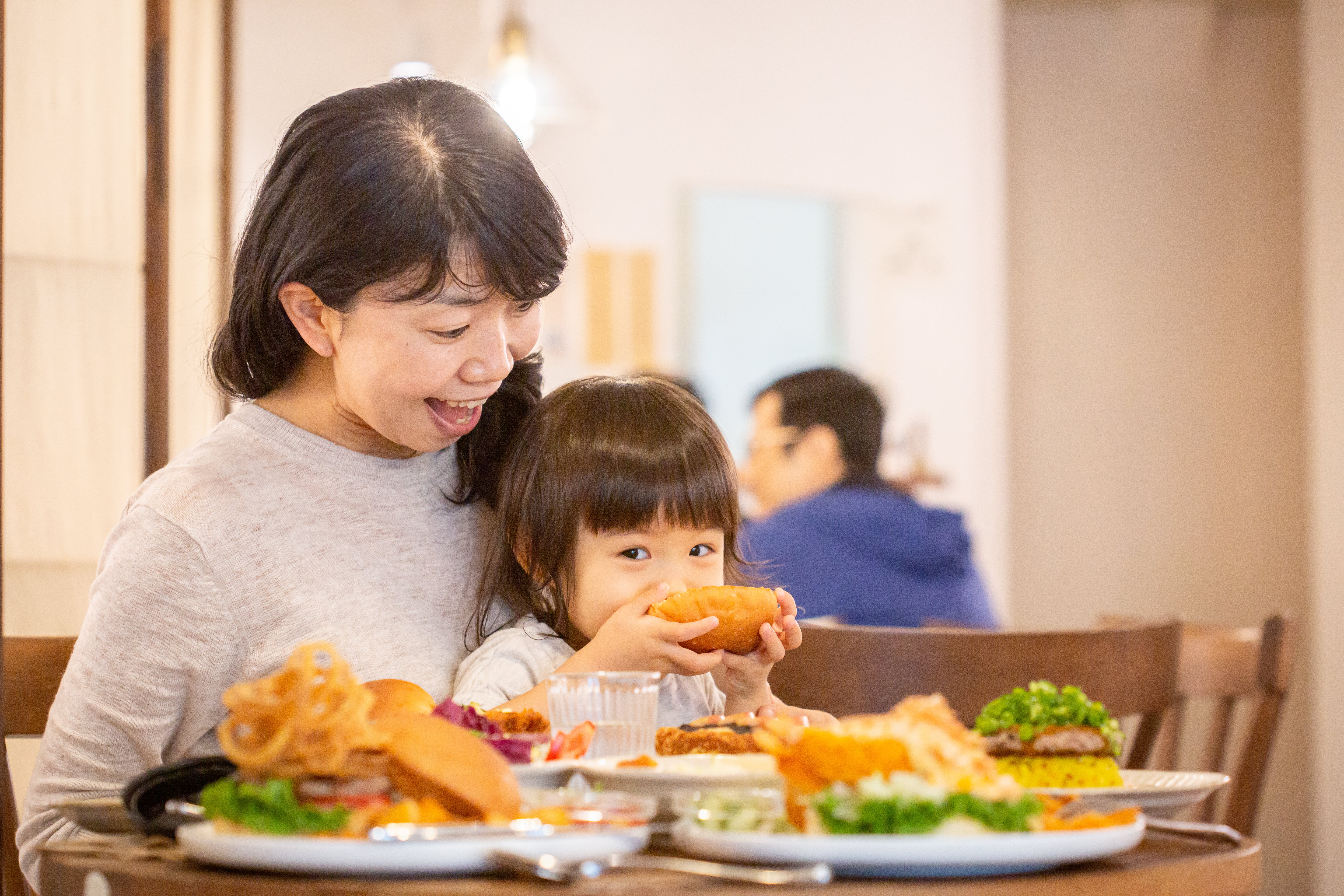 日本小女孩咬一口漢堡笑得好開心。