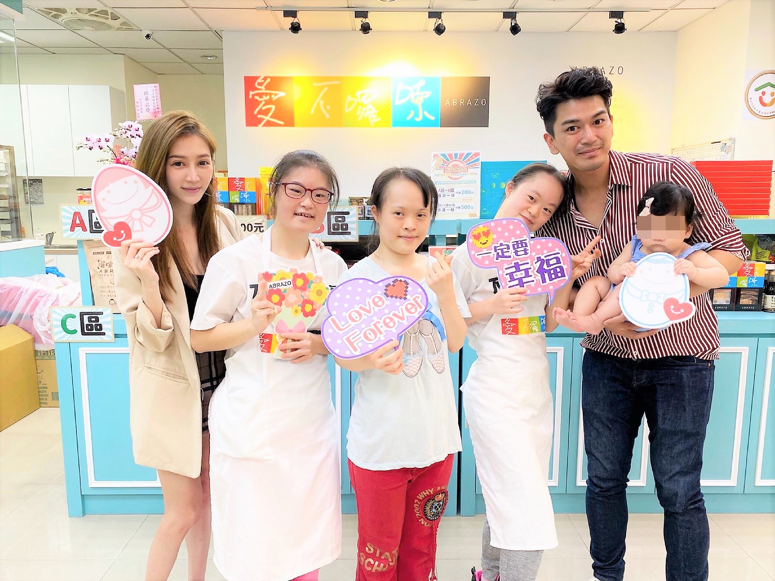 潘逸安（右）抱著女兒米估和老婆Vivian（左）一同參訪憨兒烘焙坊。（艾迪昇傳播提供）