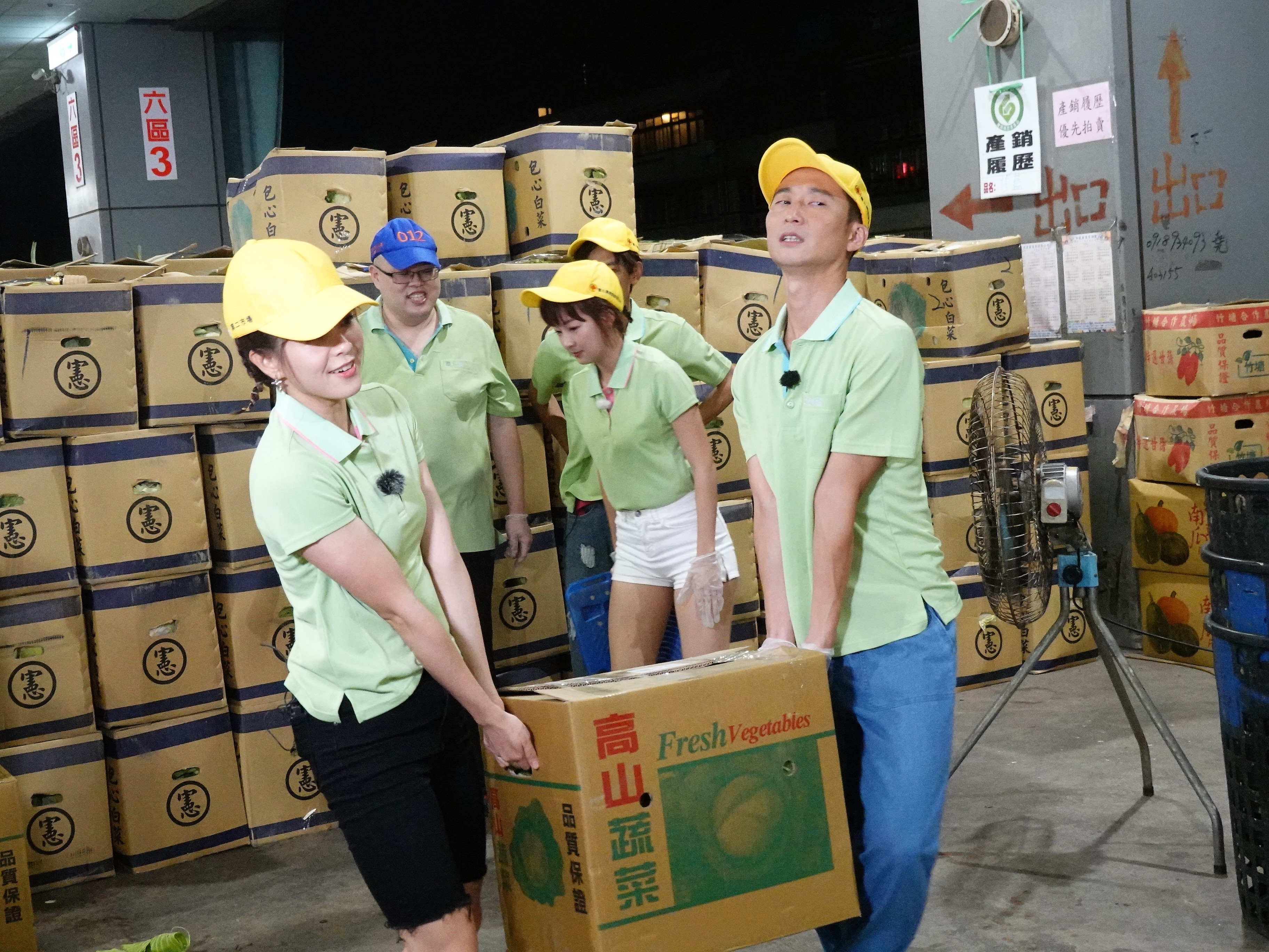 《綜藝新時代》來到北農果菜批發市場錄製，林柏妤（左）與浩子（右）試著搬運蔬菜。（民視提供）