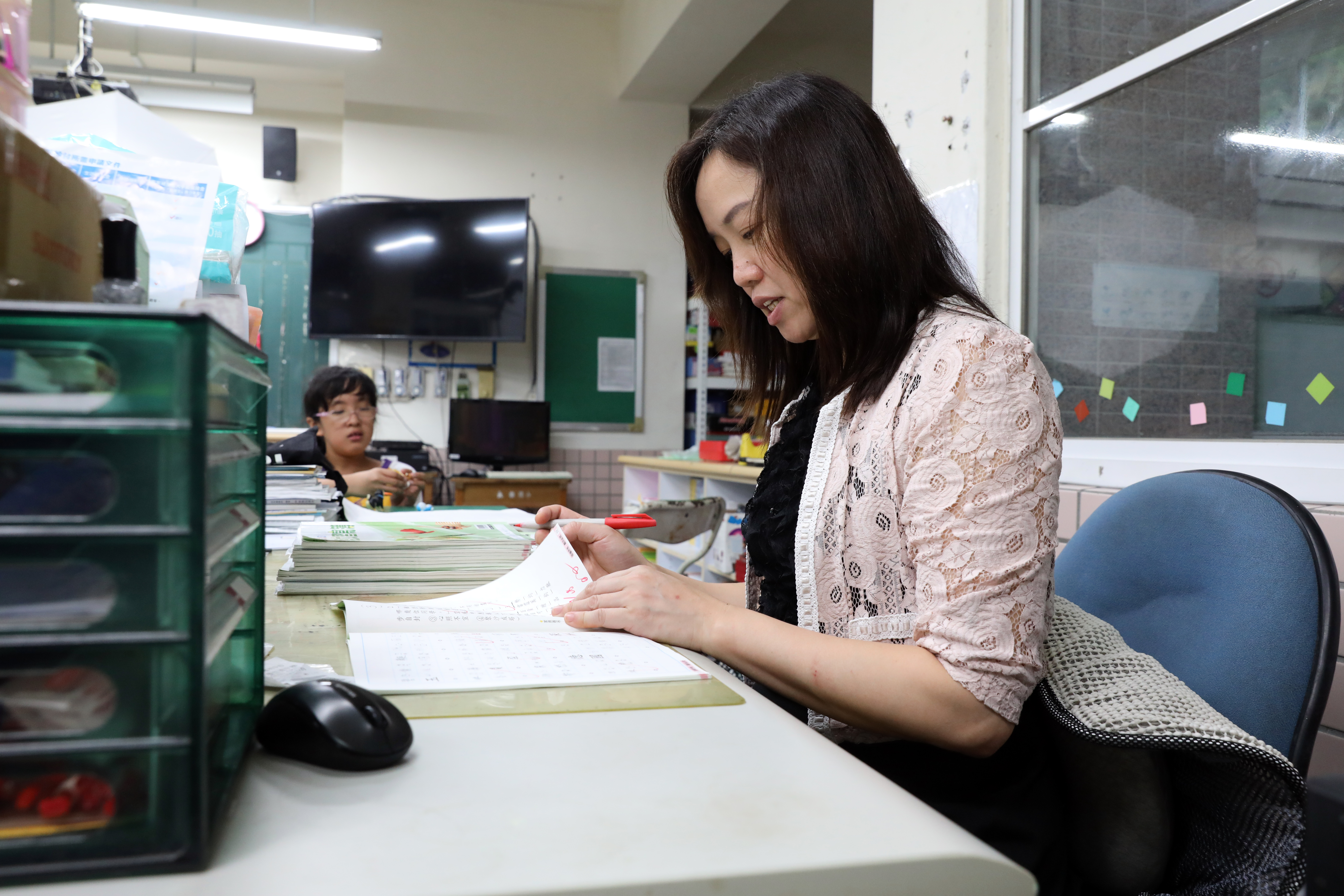 放學後，沈雅琪（右）仍在教室改作業，她的女兒在一旁陪伴，等爸爸來接她。