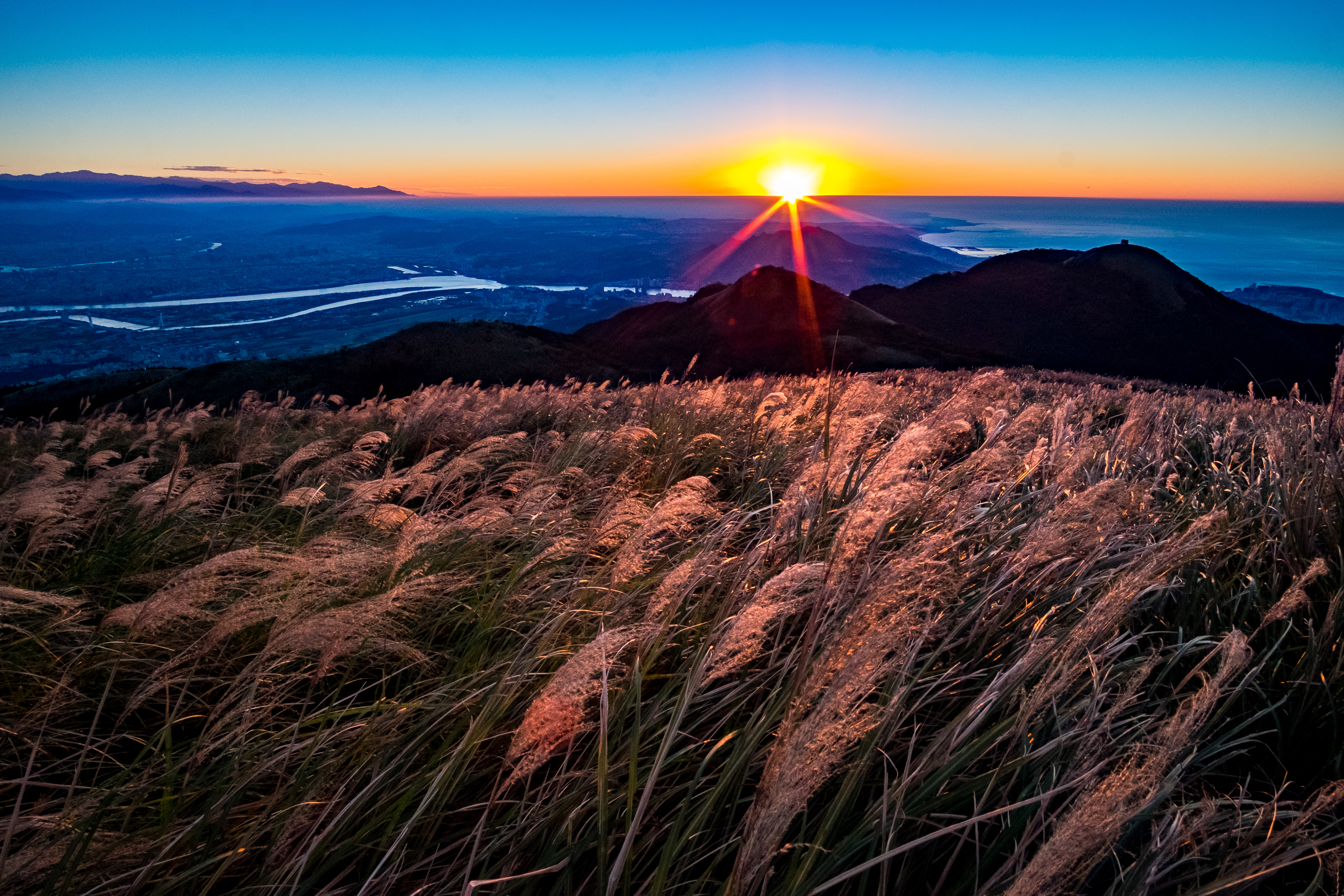 大屯山助航站旁是欣賞芒草的制高點，夕陽西下，芒草染紅的景觀很特別，後方可以一覽台北盆地的視野。