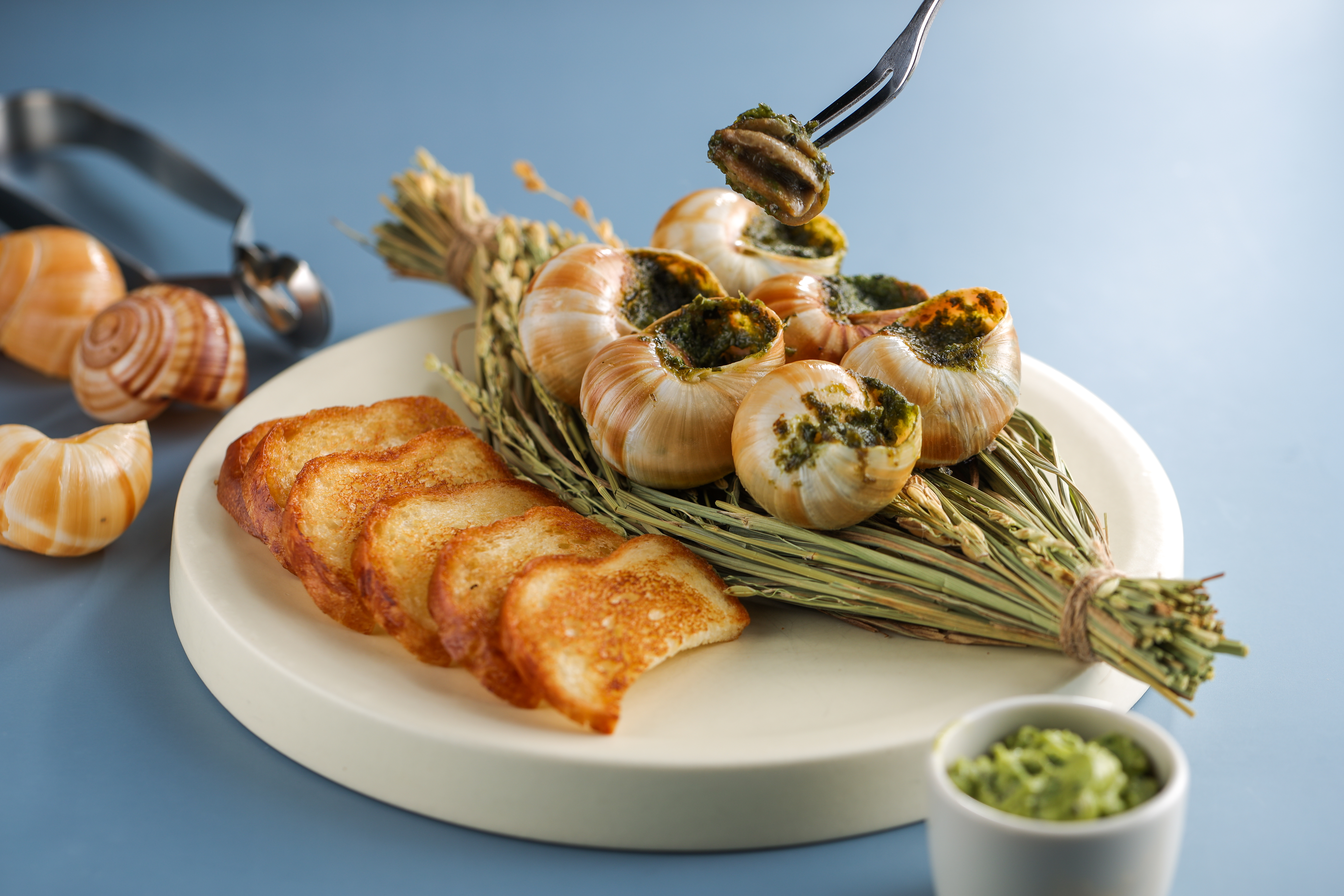 「嫩烤蝸牛配布里歐麵包」的花蓮白玉蝸牛肉質彈牙，塗上融合烤大蒜、奶油、蝦夷蔥的醬汁，將甜變化出層次。（320元／份）