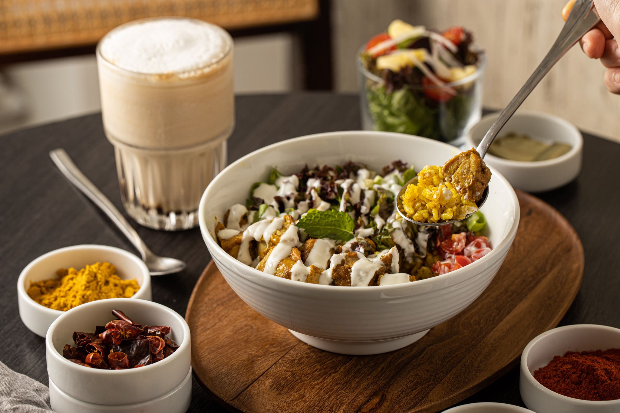 「紐約街頭雞肉飯」（前，330元／份）」採用「舒康雞」雞腿肉，肉質緊實，米飯、大麥仁飯用薑黃、薑泥炒得乾爽，非常用心。「海鹽焦糖拿鐵」（後左，140元／杯）融合自家煮的焦糖，加上巴西海鹽，甜鹹討喜。