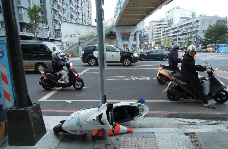 為追緝違規車輛闖紅燈，楊員不慎被撞飛，警用機車甩到路旁。（翻攝自畫面）