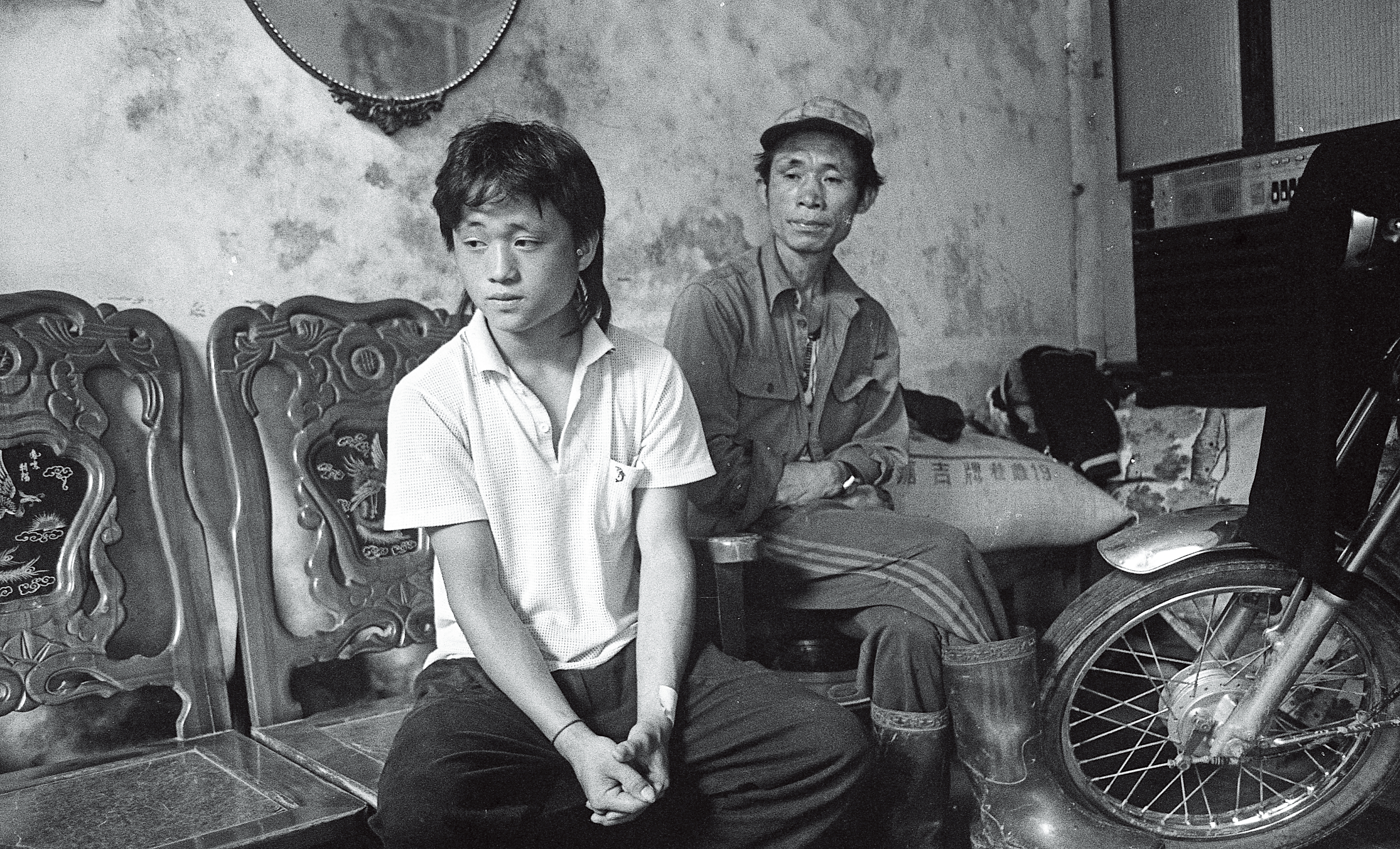 1988年,周子飛的二哥張文星(左)與生父周瑞霖(右)一同在家中接受訪問。周瑞霖因酗酒,於多年前亡故。(蔡明德攝)