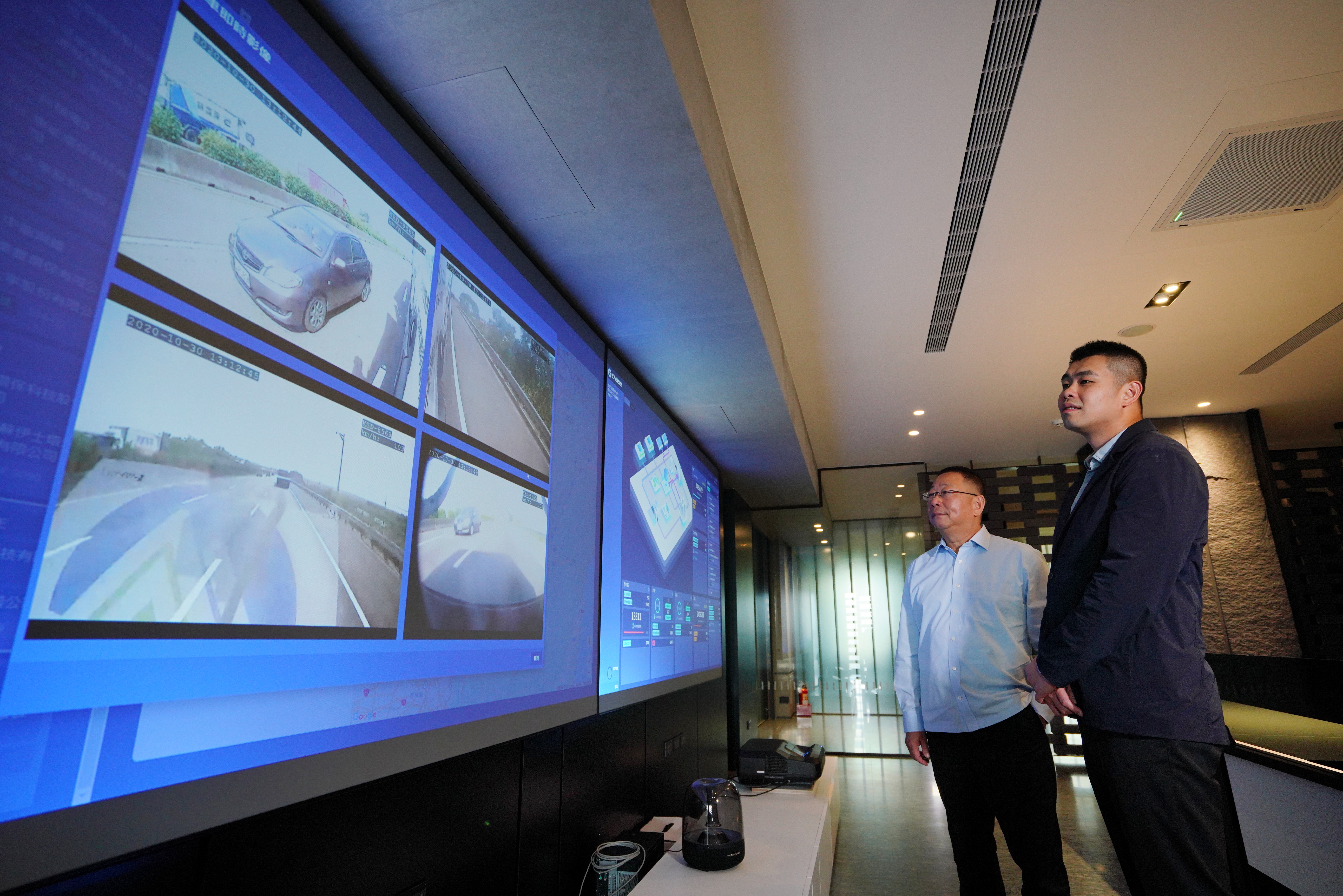 楊永發（右）與父親楊慶祥（左）站在岡山總部的戰情室前，透過大數據即時掌握，可避免廢棄物被惡意傾倒。