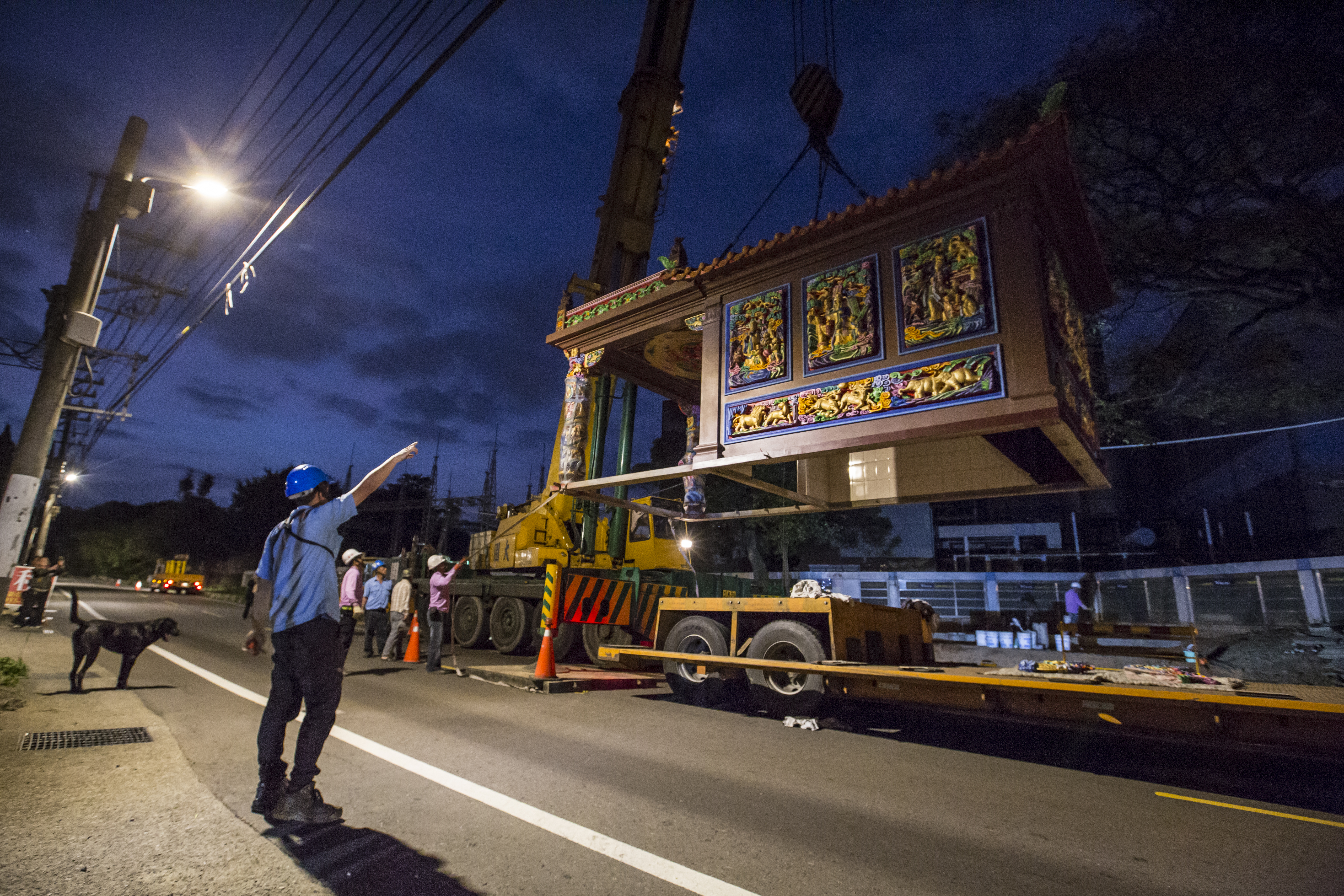 工程人員將吊車掛勾掛上廟宇屋頂，一座9坪大的土地公廟瞬間騰空而起，緩緩穿過2棵樹中間，不偏不倚地落在風水師指定的基座上。