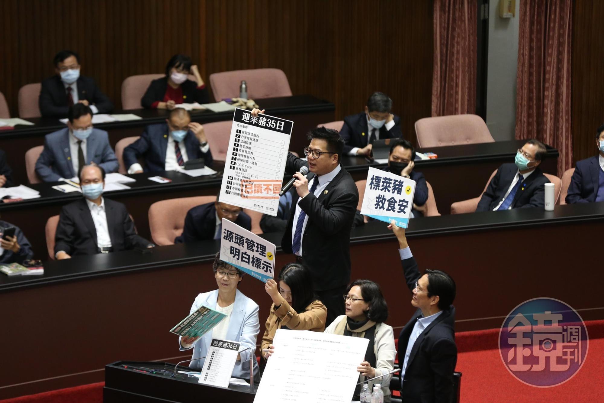 民眾黨立委邱臣遠(舉「迎萊豬35日」板者)質詢時,同黨立委在旁協助。