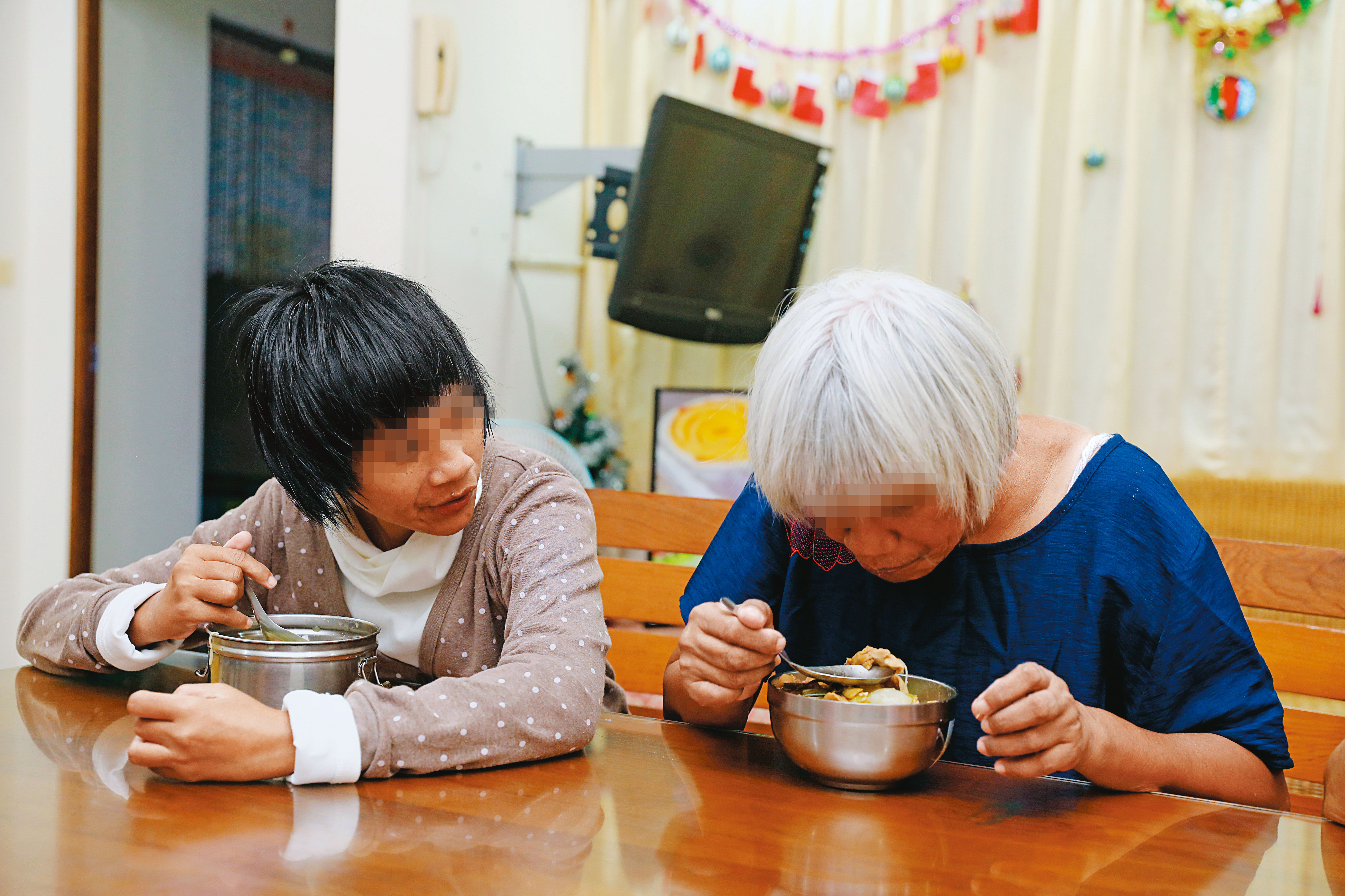 在牧心夜間照護機構，謝秀琴（右）和蔡美莉（左）一起吃飯。老憨兒體力總在午後快速衰退，沐浴、晚餐後，就無法再安排太多的活動。