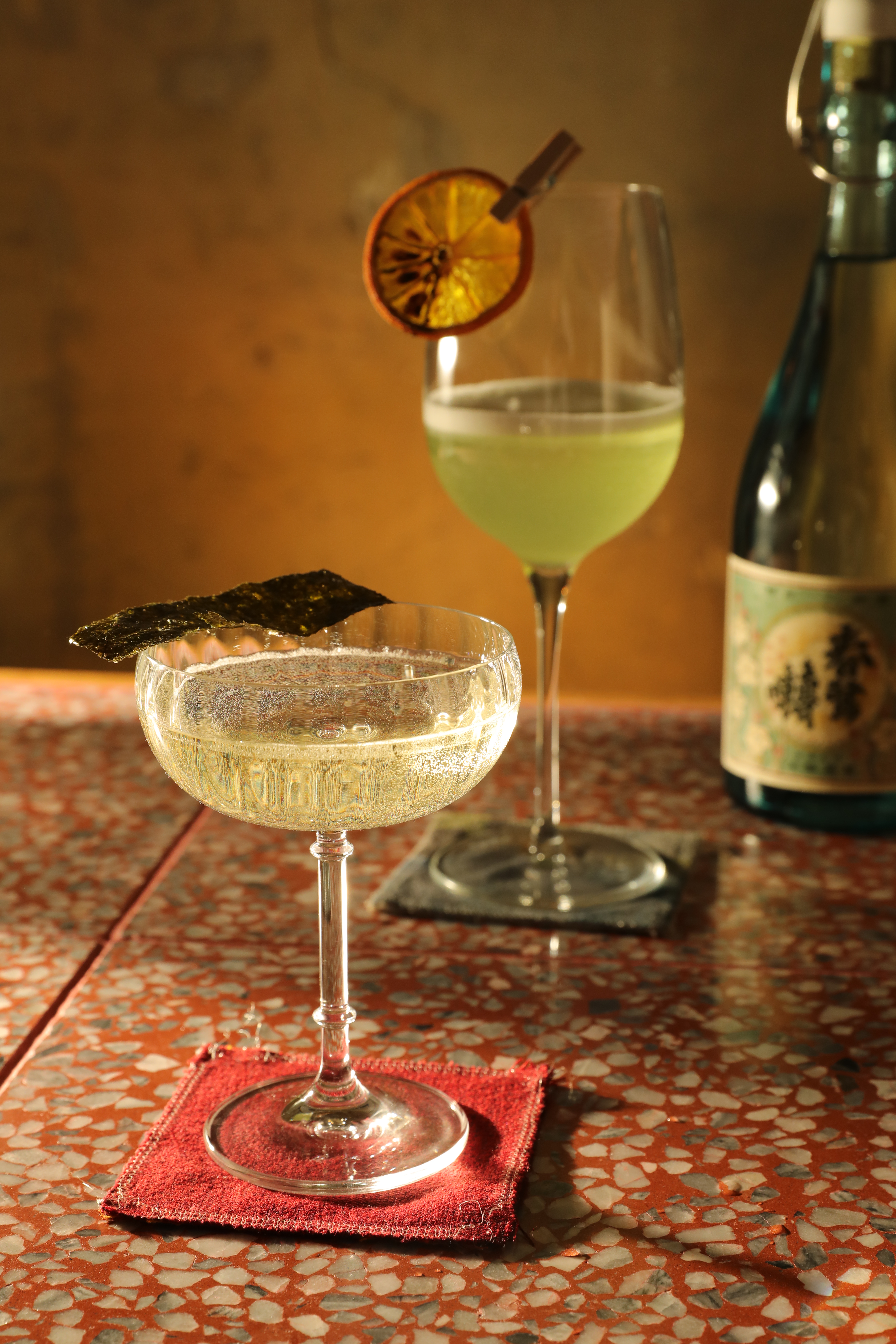 「秋香」（前，400元／杯）以「春鶯囀純米酒」（右後）為底，加入醃漬蘿蔔的醋水、木質調性利口酒，宛如冷湯。「熏在蔬果舖」（後，400元／杯）的基酒是「八神峰 純米清酒」，融合紫蘇梅酒、青蘋果利口酒、萊姆汁，果味豐盈。