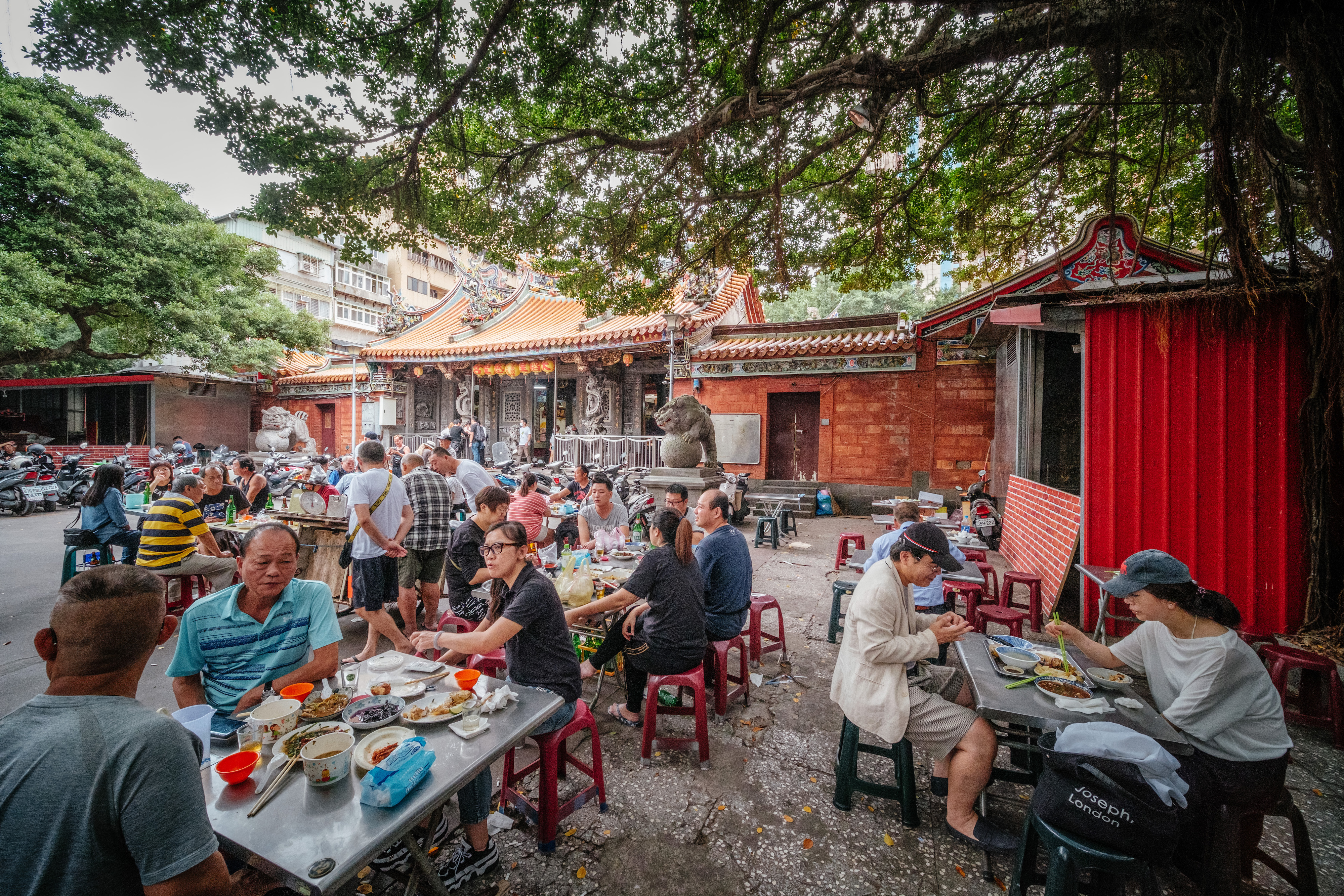 集中在慈聖宮媽祖廟前的廣場上，饕客們坐在榕樹下聊天吃著銅板美食。