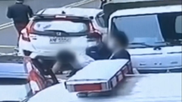 籍嫌在等候警車時，頻頻與車內友人聊天，另一名男性友人則突襲戒護員警。（翻攝畫面）