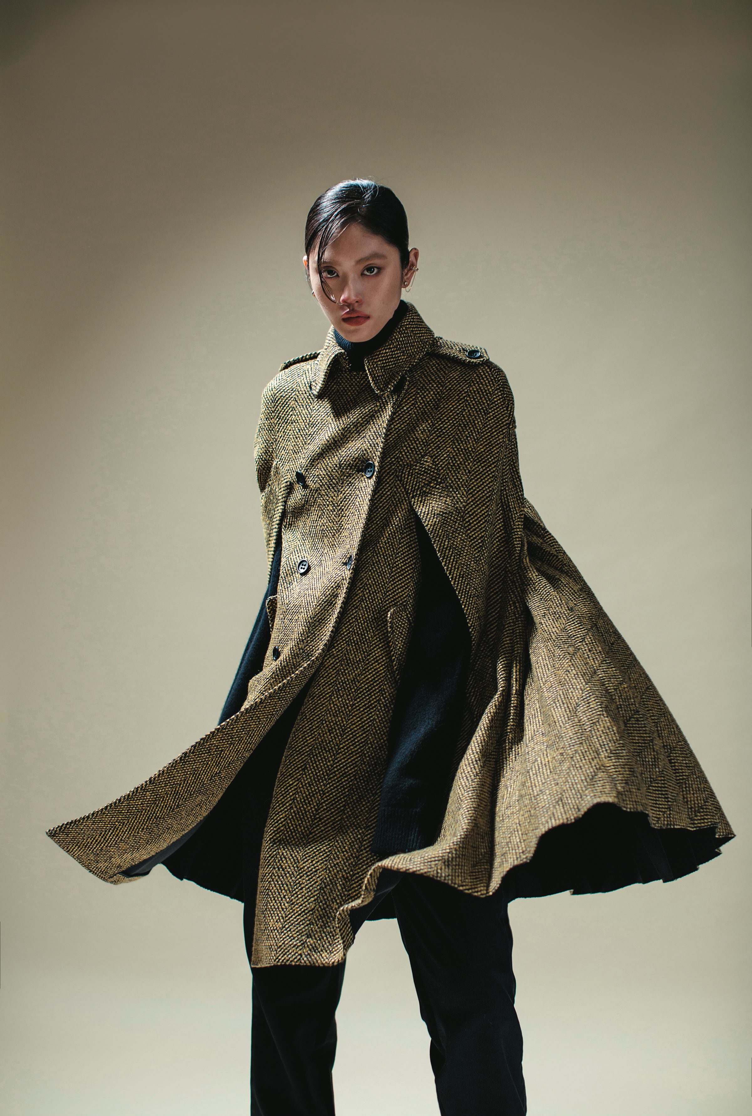黃色格紋斗篷 價格店洽 by REDValentino／黑色高領毛衣 價格店洽 by MICHAEL MICHAEL KORS／黑色長褲 價格店洽 by LOEWE／TIME穿孔耳環 NT$3,490 by SWAROVSKI