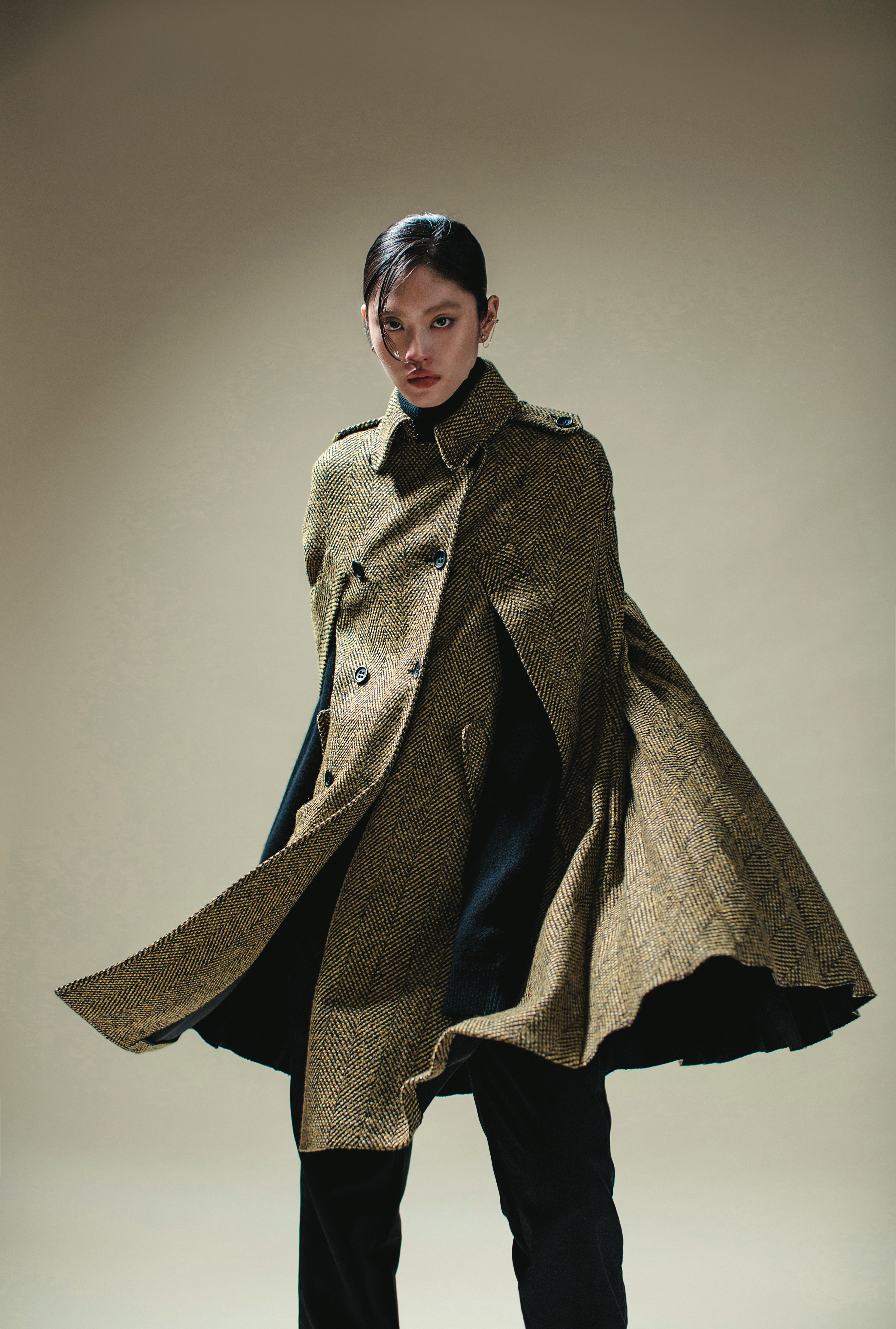 黃色格紋斗篷 價格店洽 by REDValentino／黑色高領毛衣 價格店洽 by MICHAEL MICHAEL KORS／黑色長褲 價格店洽 by LOEWE／TIME穿孔耳環 NT$3,490 by SWAROVSKI