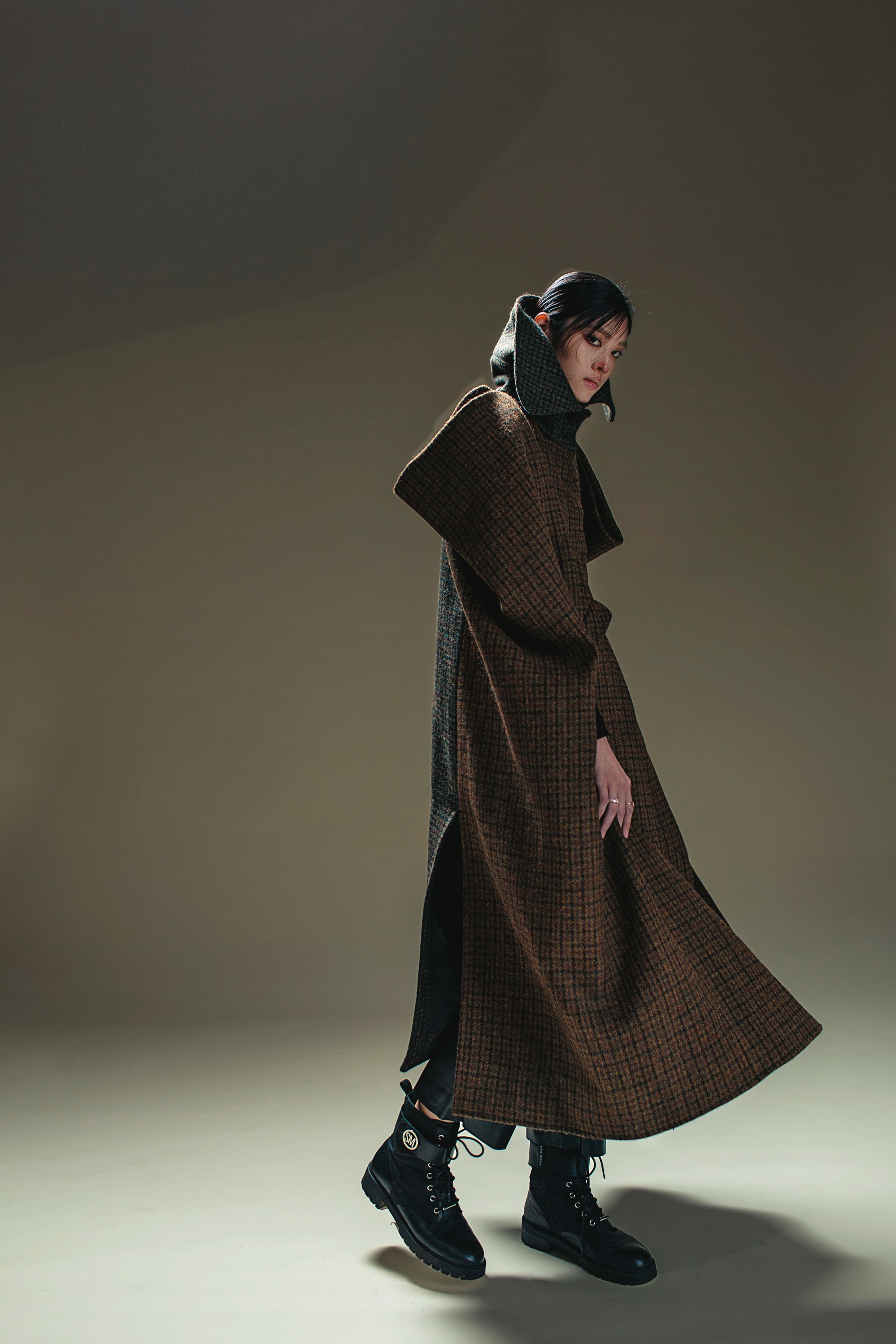 立體剪裁格紋拼接斗篷 價格店洽 by LOEWE／黑色皮長褲 NT$22,950 by SANDRO／黑色靴子 私物／VITTORE戒指 NT$6,490 by SWAROVSKI／MAGIC戒指 NT$5,990 by SWAROVSKI
