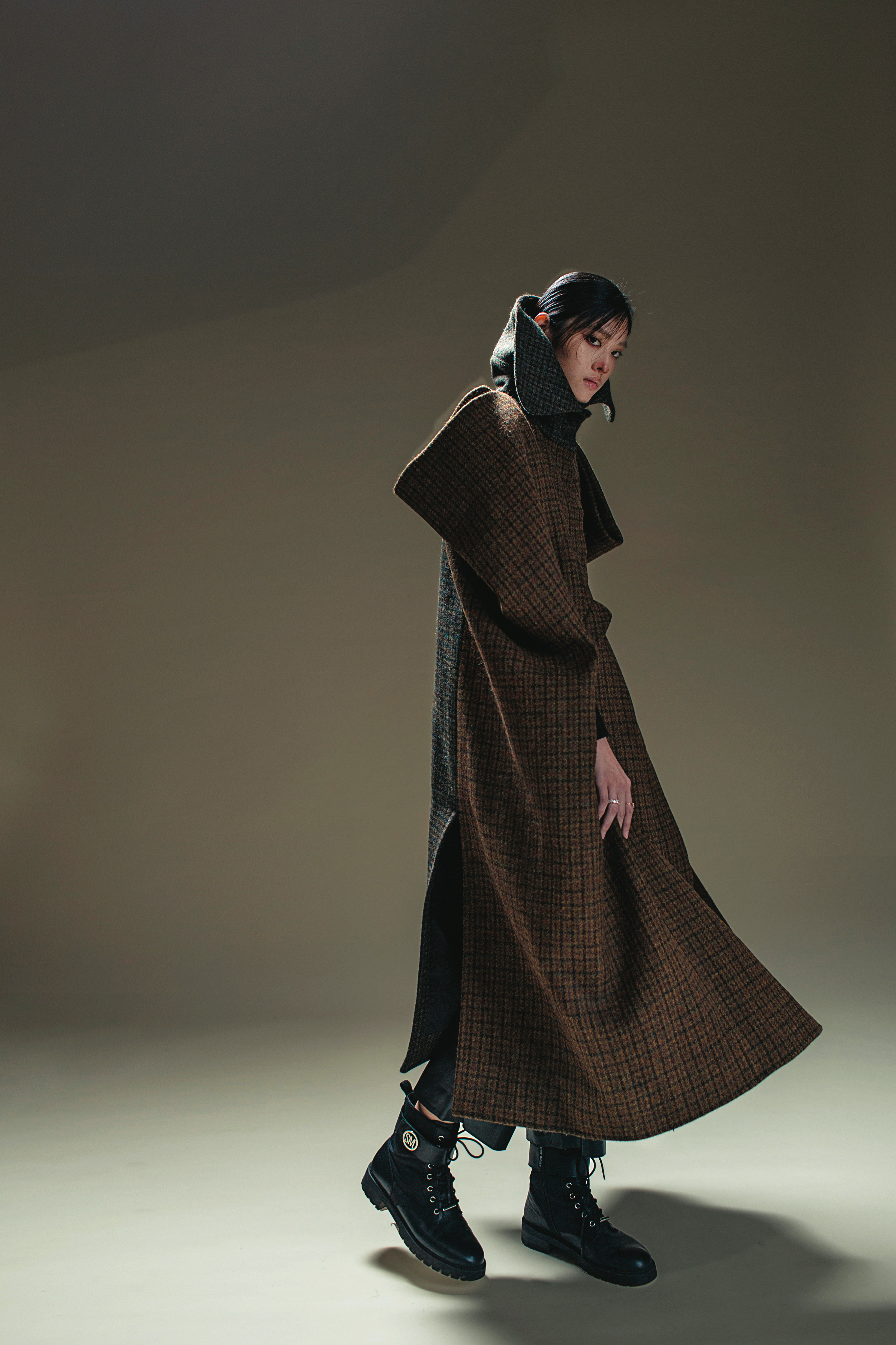 立體剪裁格紋拼接斗篷 價格店洽 by LOEWE／黑色皮長褲 NT$22,950 by SANDRO／黑色靴子 私物／VITTORE戒指 NT$6,490 by SWAROVSKI／MAGIC戒指 NT$5,990 by SWAROVSKI