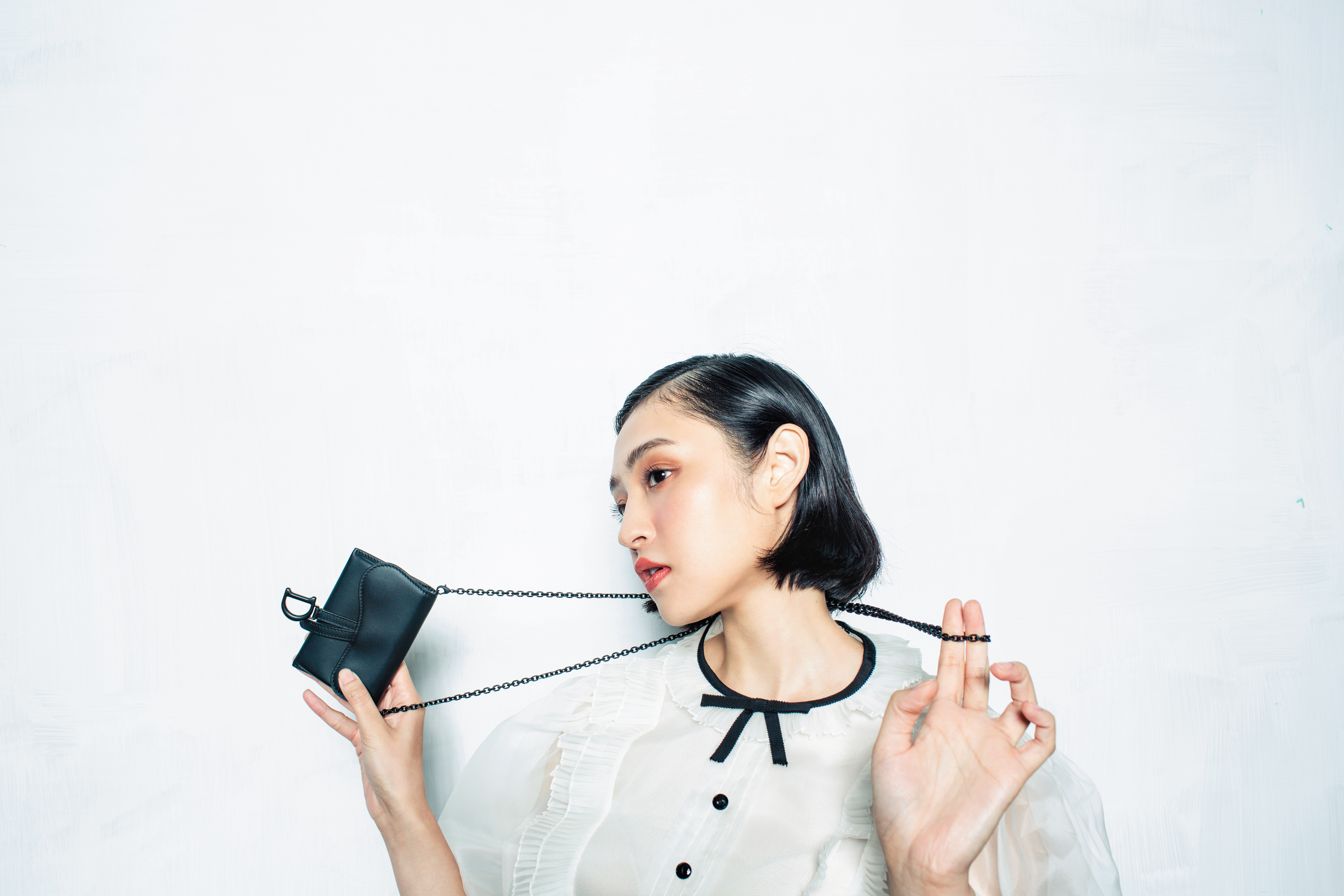 Saddle Ultra Matte黑色小牛皮馬鞍鍊帶手拿包NT$25,000 by Dior;荷葉領燈籠袖洋裝NT$83,000 by MIU MIU。