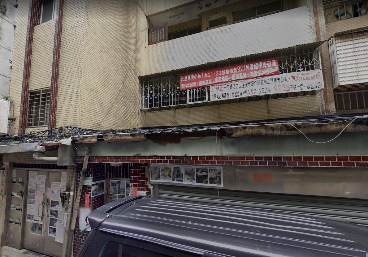 北市中山區的海砂屋外,貼滿「921列管海砂屋」的照片及紅布條。(翻攝畫面)