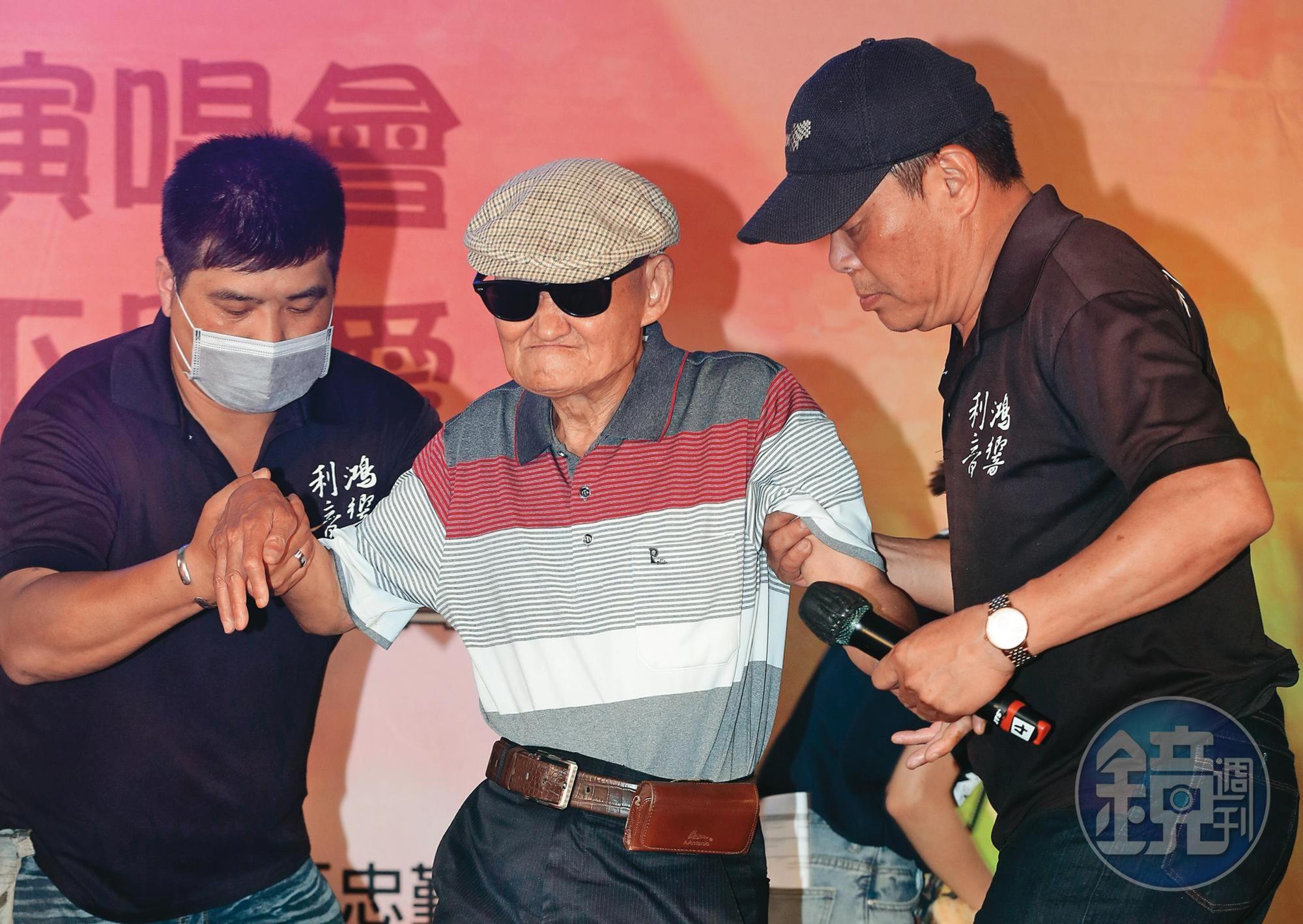 李炳輝(中)因二度中風行動不便,需旁人攙扶,且他因台北陰雨綿綿,氣候不佳,街頭演出受阻。