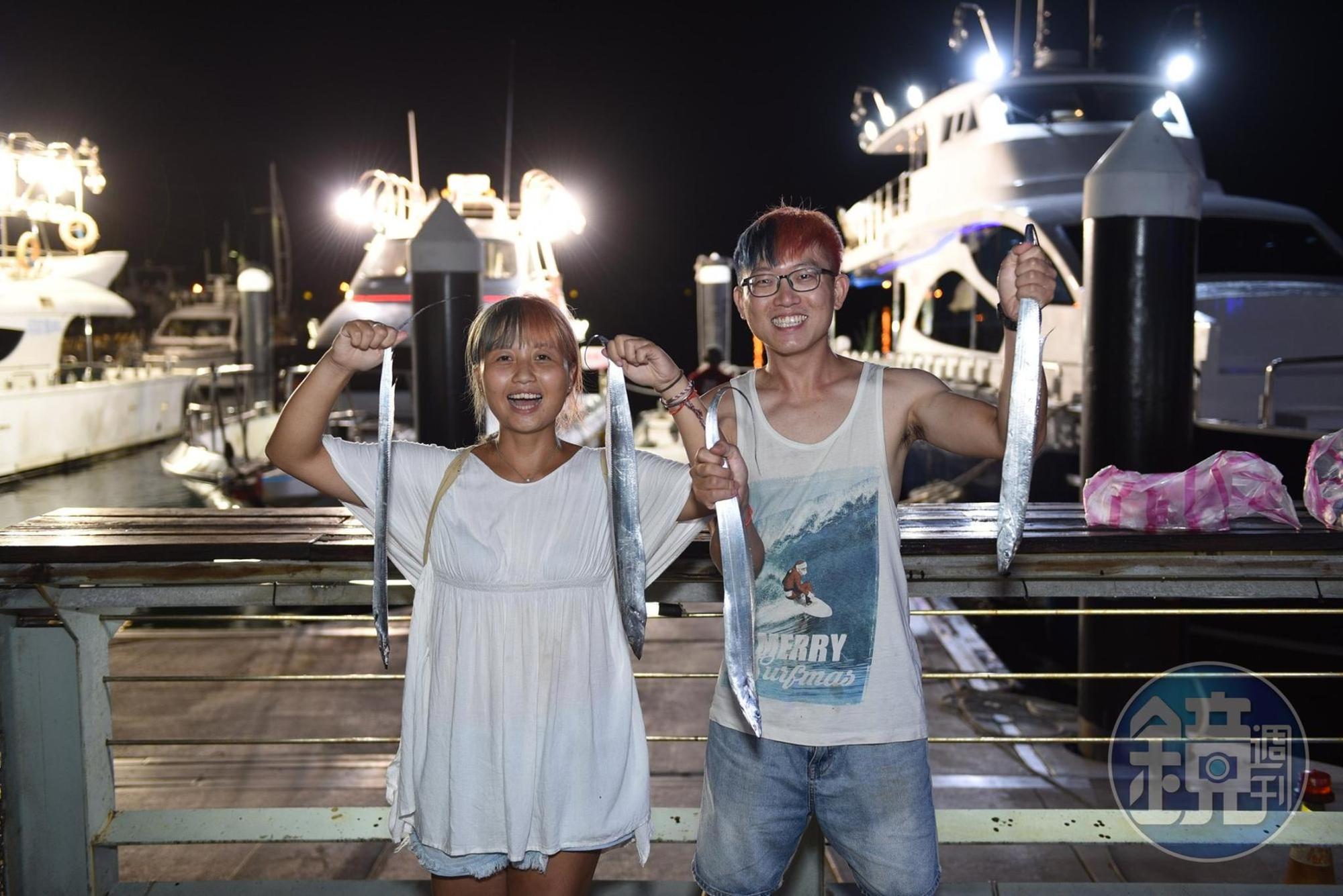 生手夜釣白帶魚,高舉戰利品。
