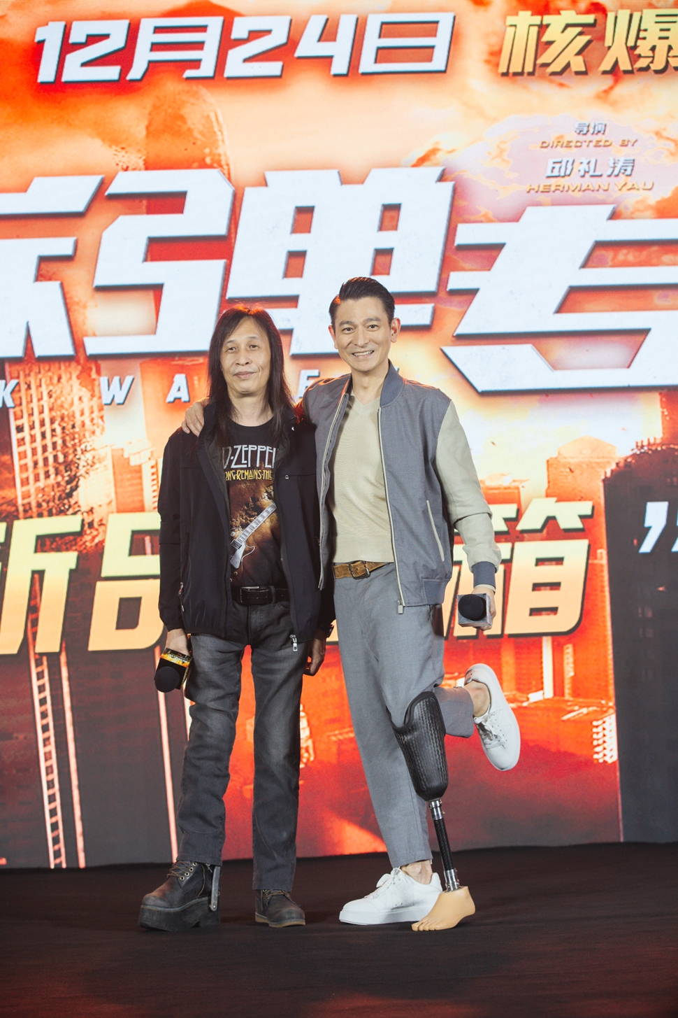 《拆彈專家2》記者會上,導演邱禮濤(左)與帶著戲中道具義肢出席的劉德華。(華映提供)