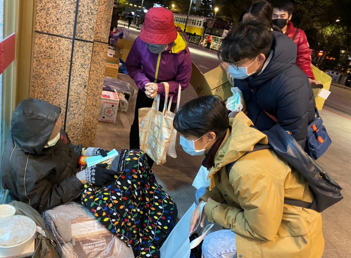 慈濟志工陳雲貞、慈科大校友趙軒、趙悅、張家瑜(左二起)送口罩及暖暖包給街友。(慈濟提供)