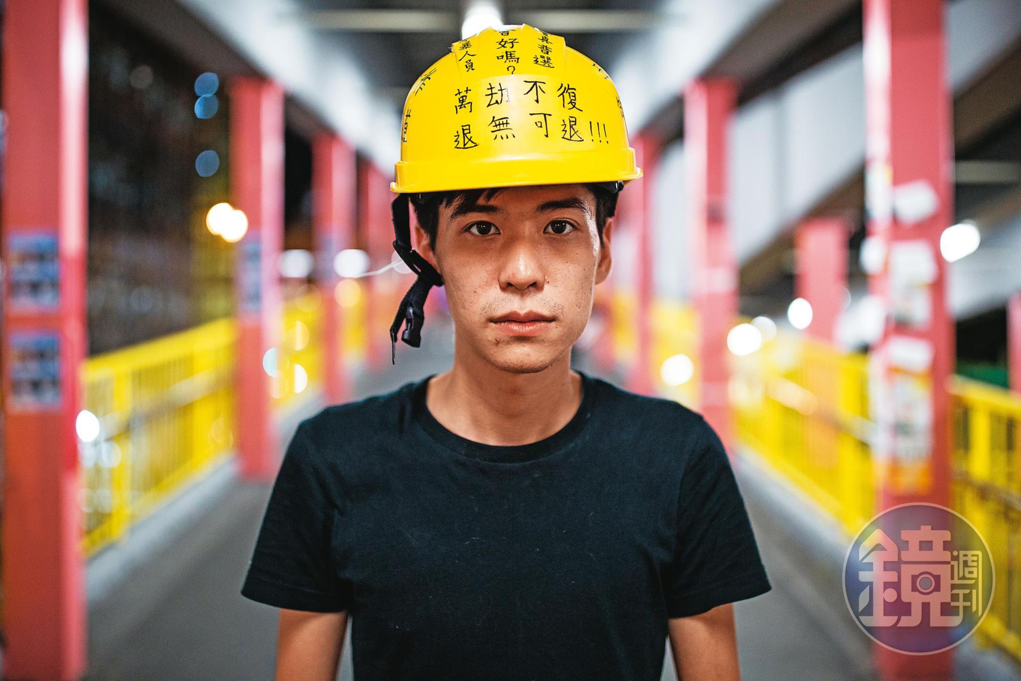 2019年反修例運動期間,岑敖暉接受本刊專訪後站在一處地鐵站拍照,頭上安全帽寫著抗爭標語。