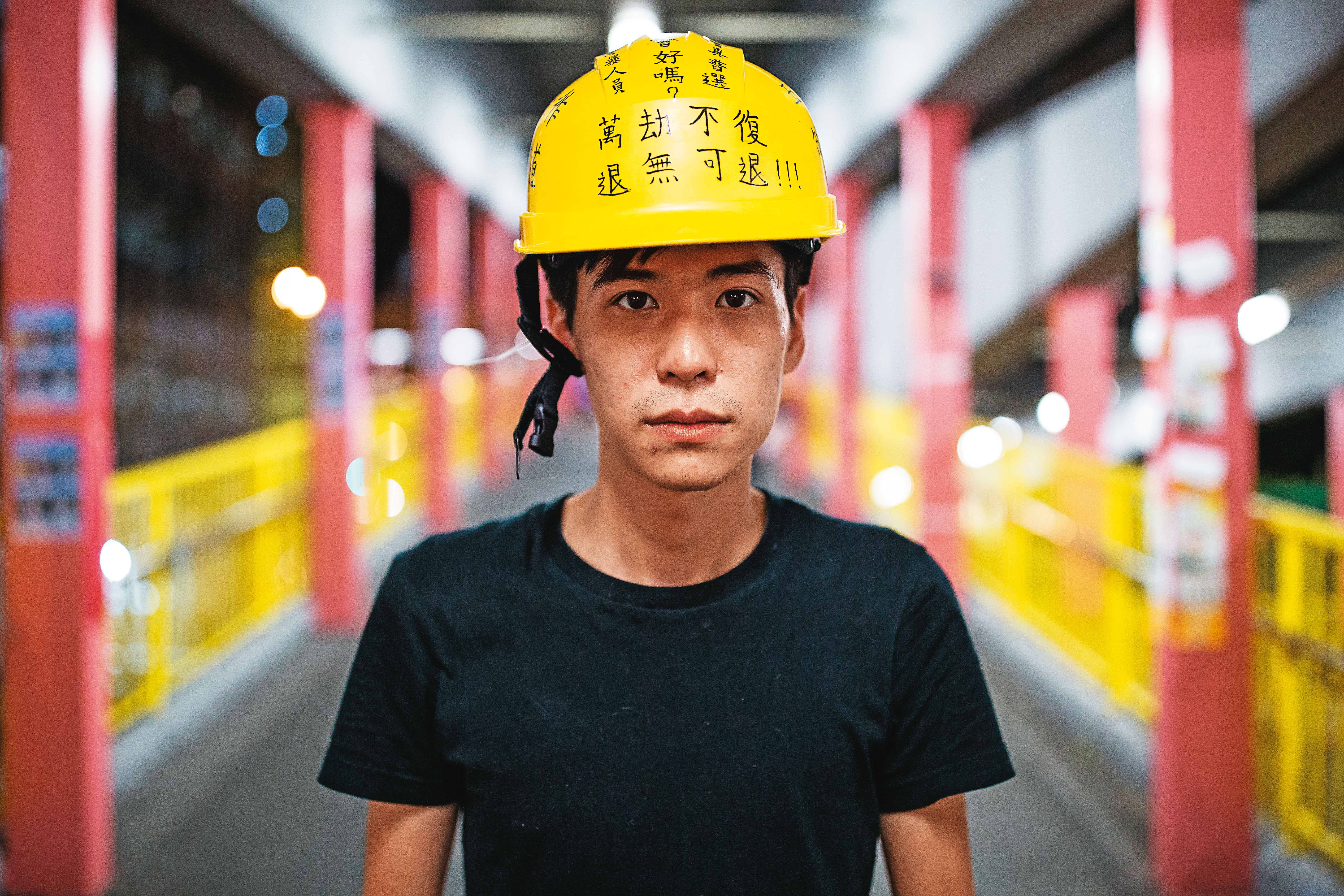 2019年反修例運動期間,岑敖暉接受本刊專訪後站在一處地鐵站拍照,頭上安全帽寫著抗爭標語。