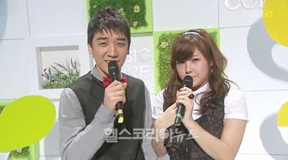 松雨（右）和勝利主持《MUSIC CORE》時因腫脹的臉部而引發觀眾熱議。（翻攝自healthkorea news）