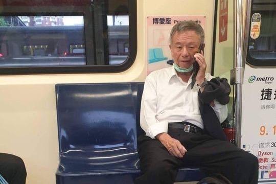 有粉專貼出楊志良搭乘捷運時,為講電話而拉下口罩的照片。(翻攝自水鏡政經學院臉書)