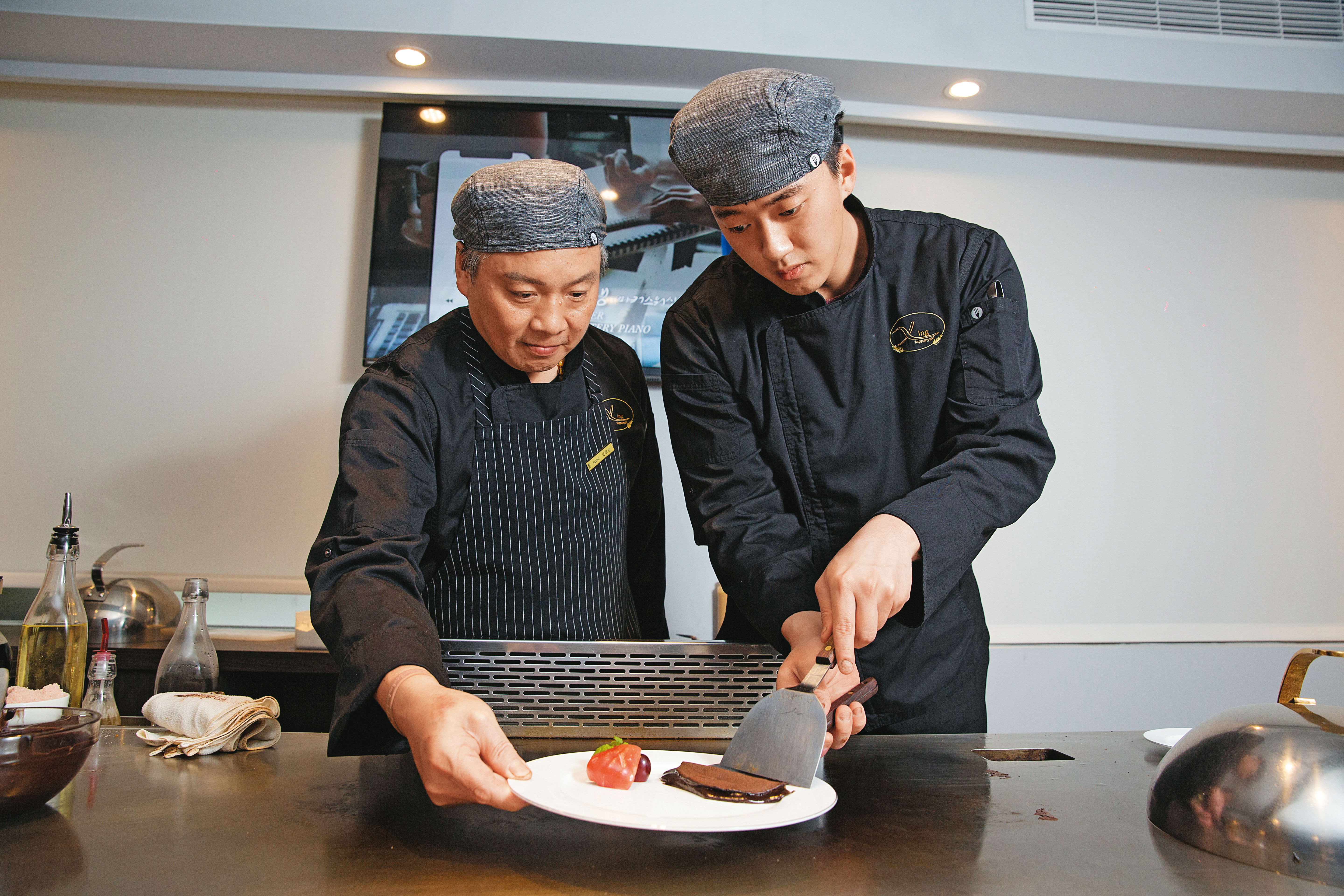 阿興師（左）的兒子（右）這2年也跟在他身邊學功夫，可獨立完成甜點熔岩巧克力。