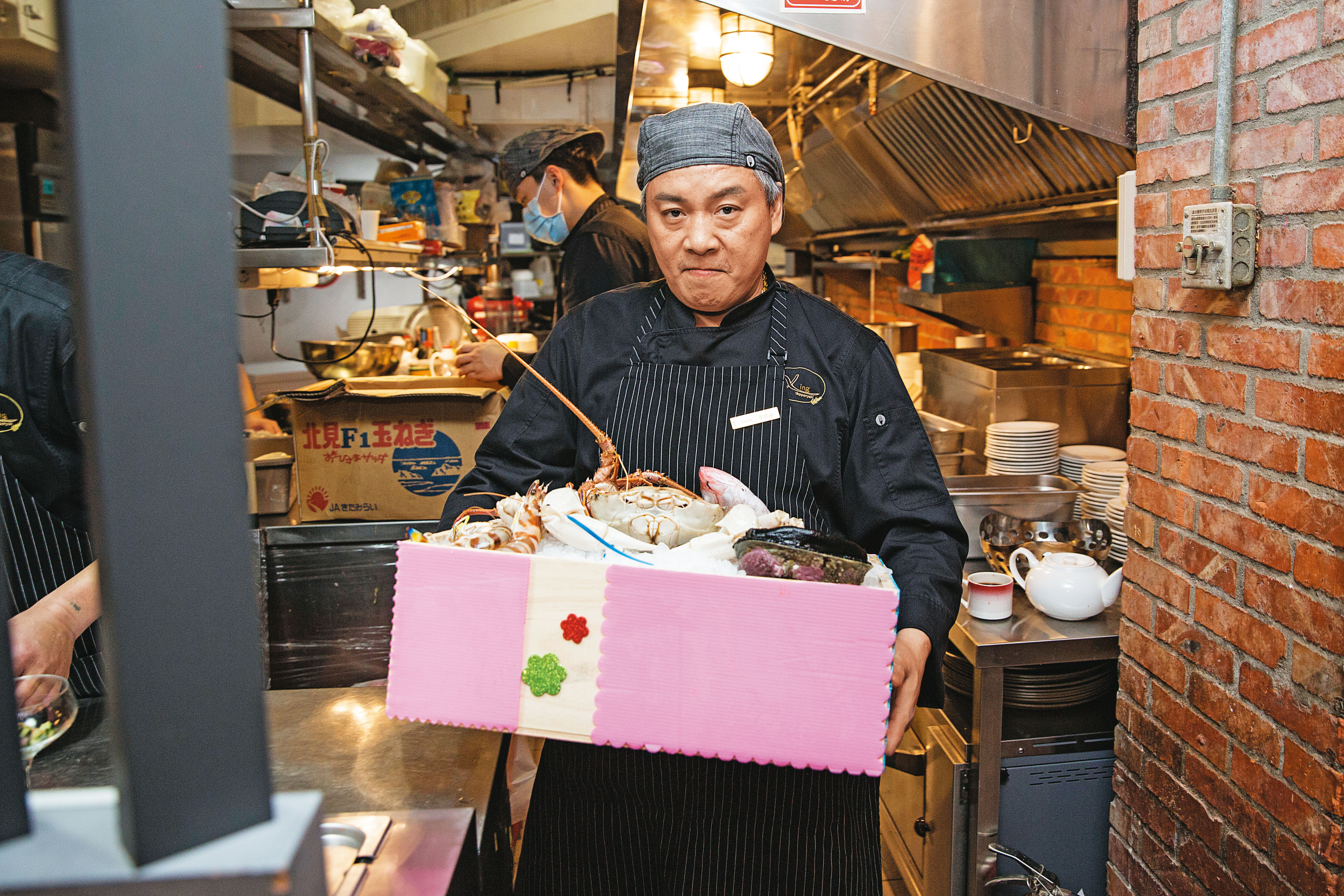 阿興師傅搬出一箱時令頂鮮食材，要去煎檯秀給客人看。鱈場蟹、活鮑魚都需提前預訂。