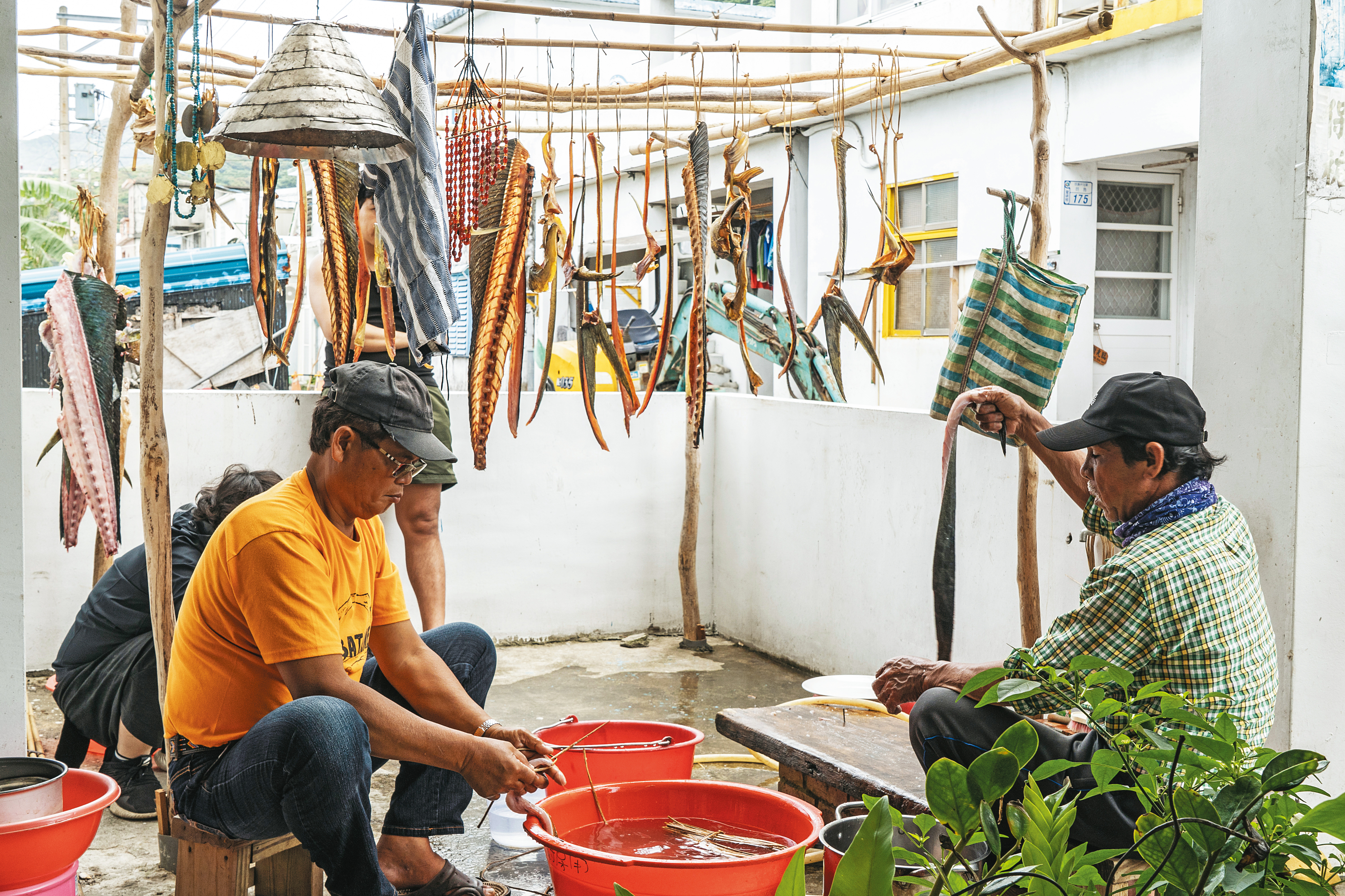 謝永泉（左）與友人在家門口處理捕到的飛魚。（鄭宇騏攝）