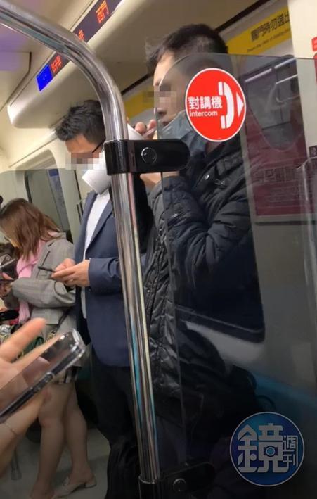 一名身穿黑色外套男子在捷運車廂內拉下口罩狂喝飲料。(讀者提供)