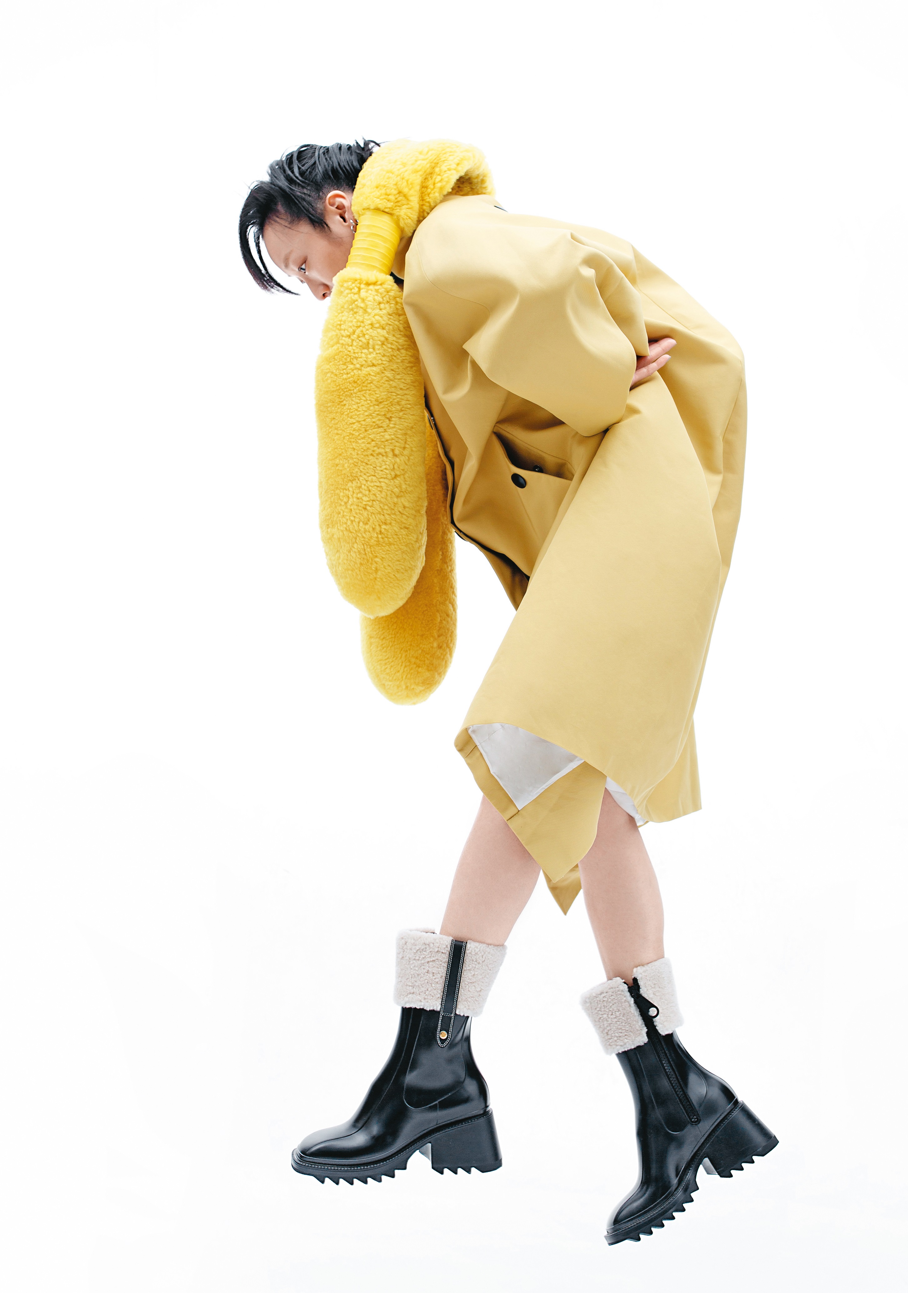黃色防水風衣 NT$115,000 by PRADA／黃色翻羊毛長脖圍巾 NT$50,100 by BOTTEGA VENETA／Betty黑色羔羊毛飾邊雨靴 NT$19,800 by CHLOÉ