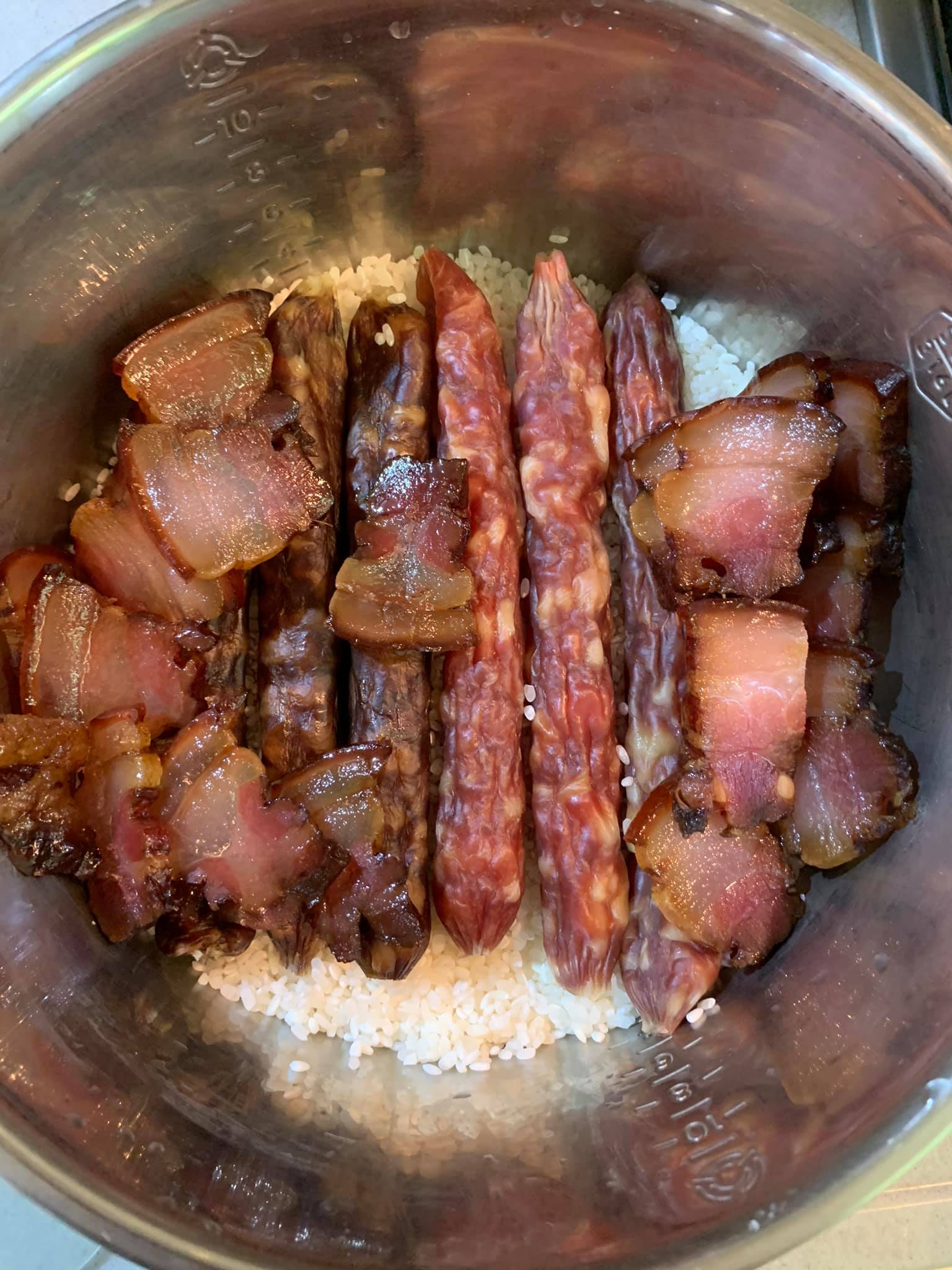 將臘腸、肝腸、臘肉放在米上，之後再加水。