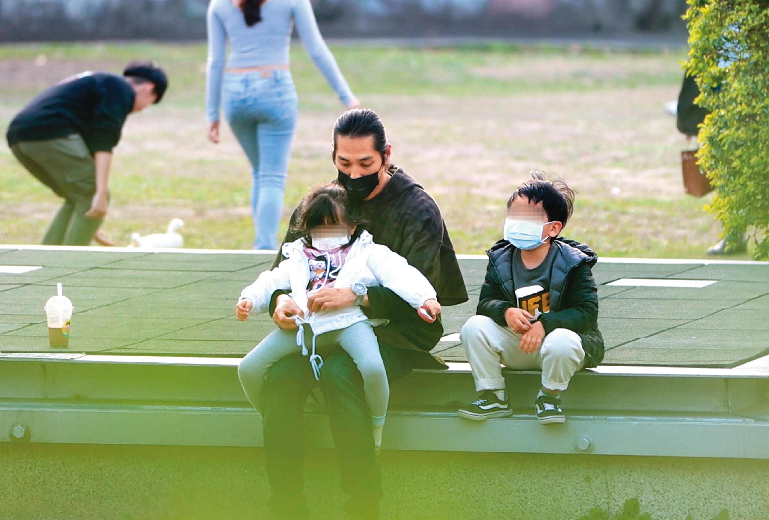 1/25 15:48 兩個孩子終於玩累，藍正龍抱著女兒坐在草地旁邊，呈現一副天倫美好。